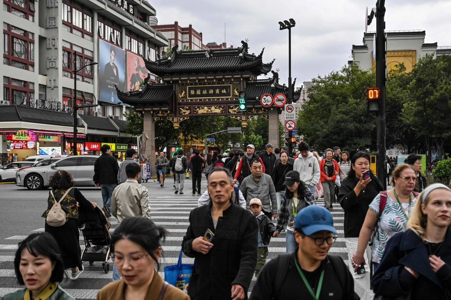 مشاة في أحد الشوارع التجارية المزدحمة بمدينة شنغهاي الصينية (أ.ف.ب)