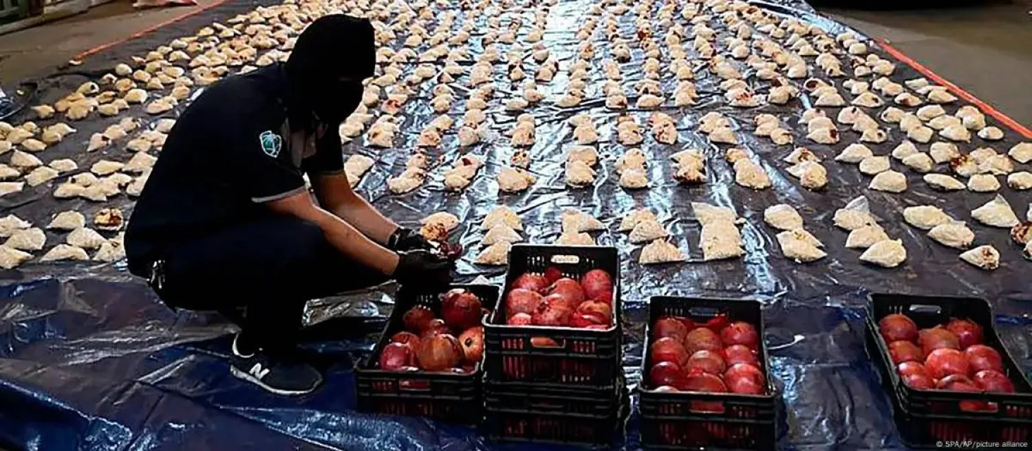 عنصر أمن سعودي يعرض المخدرات المضبوطة في ثمرات رمان انطلقت من لبنان وضُبطت في السعودية عام 2021 (أرشيفية - أ.ب)