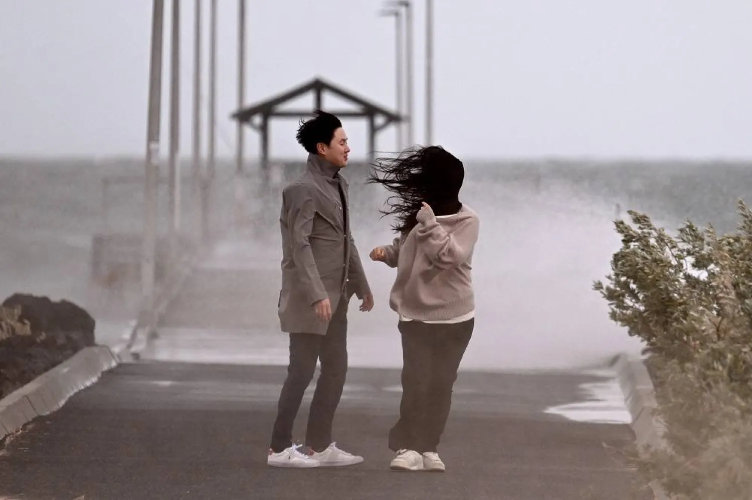 People stand near a jetty amid a stormy weather in Melbourne on October 22, 2025. (AFP)