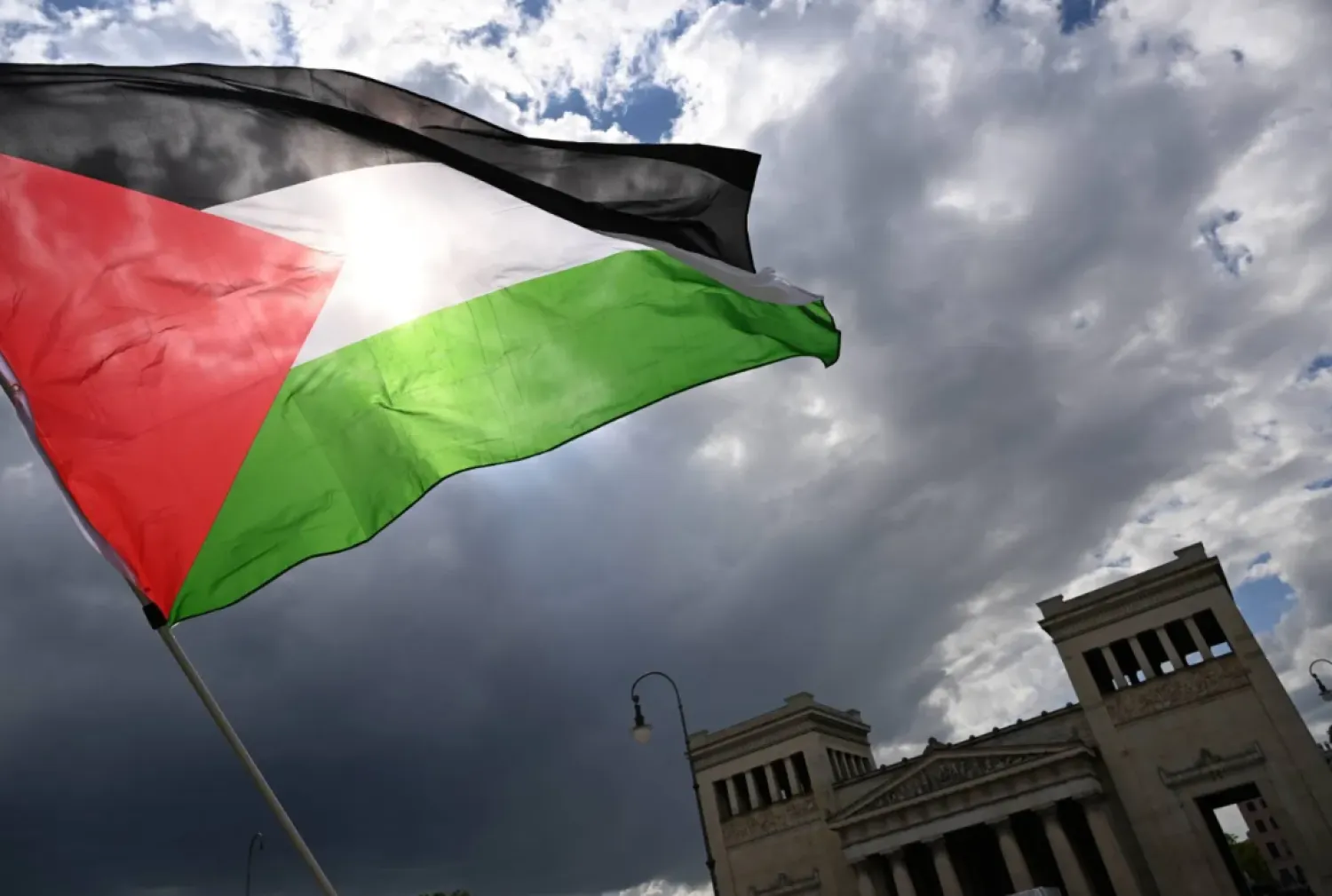 17 May 2025, Bavaria, Munich: A protester waves a Palestinian flag during a demonstration on Koenigsplatz. (dpa)
