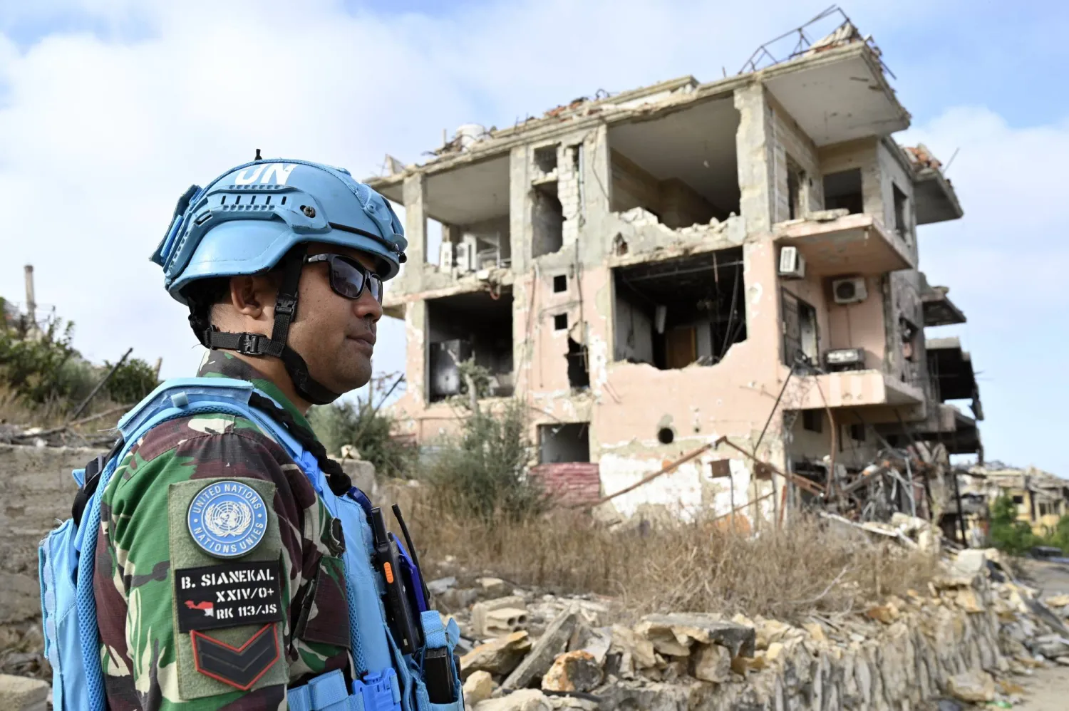 جندي من قوة الأمم المتحدة المؤقتة في لبنان (اليونيفيل) يقف بجانب أنقاض المباني المدمرة في قرية العديسة بجنوب لبنان (إ.ب.أ)