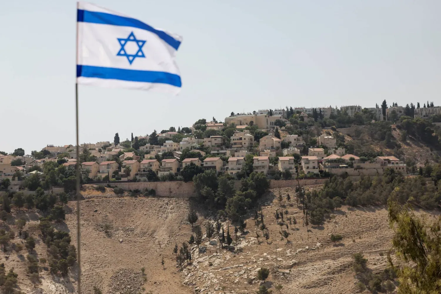 İşgal altında bulunan Batı Şeria'daki Ma'ale Adumim yerleşiminde göndere çekilen İsrail bayrağı, 14 Ağustos 2025 (Reuters)