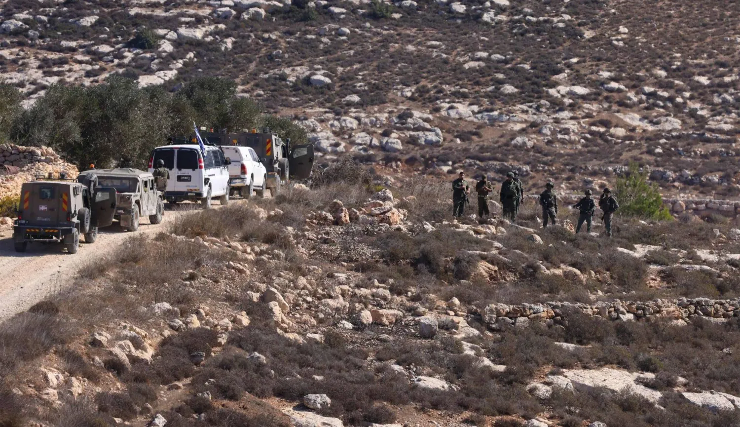 جنود إسرائيليون يتمركزون في قرية على مشارف رام الله بينما يحصد فلسطينيون الزيتون الاثنين الماضي (أ.ف.ب)