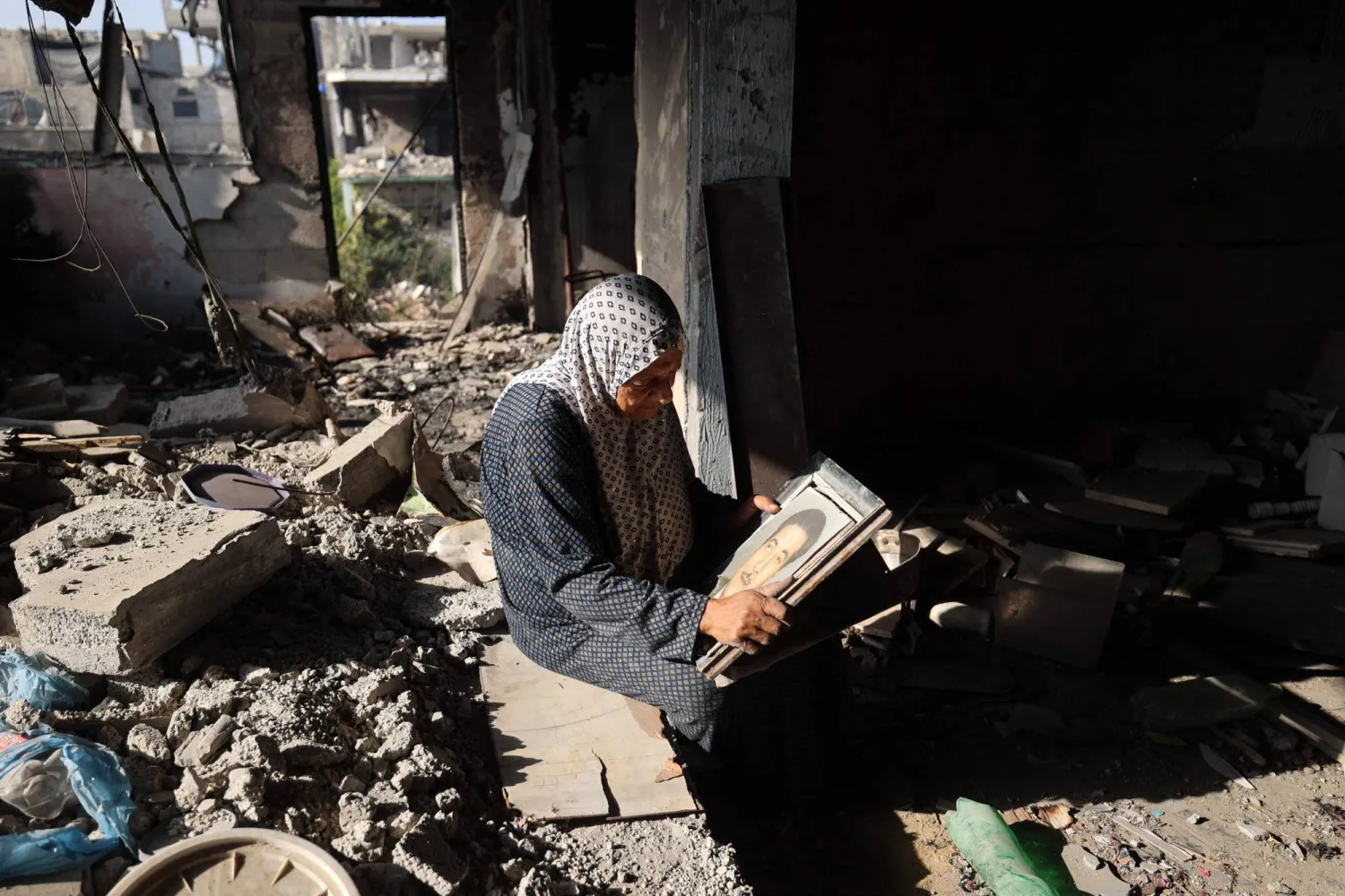 فلسطينية تمعن النظر في صورة والدها وسط ركام بيتها الذي عادت إليه في مخيم البريج بوسط قطاع غزة يوم الخميس (أ.ف.ب) 