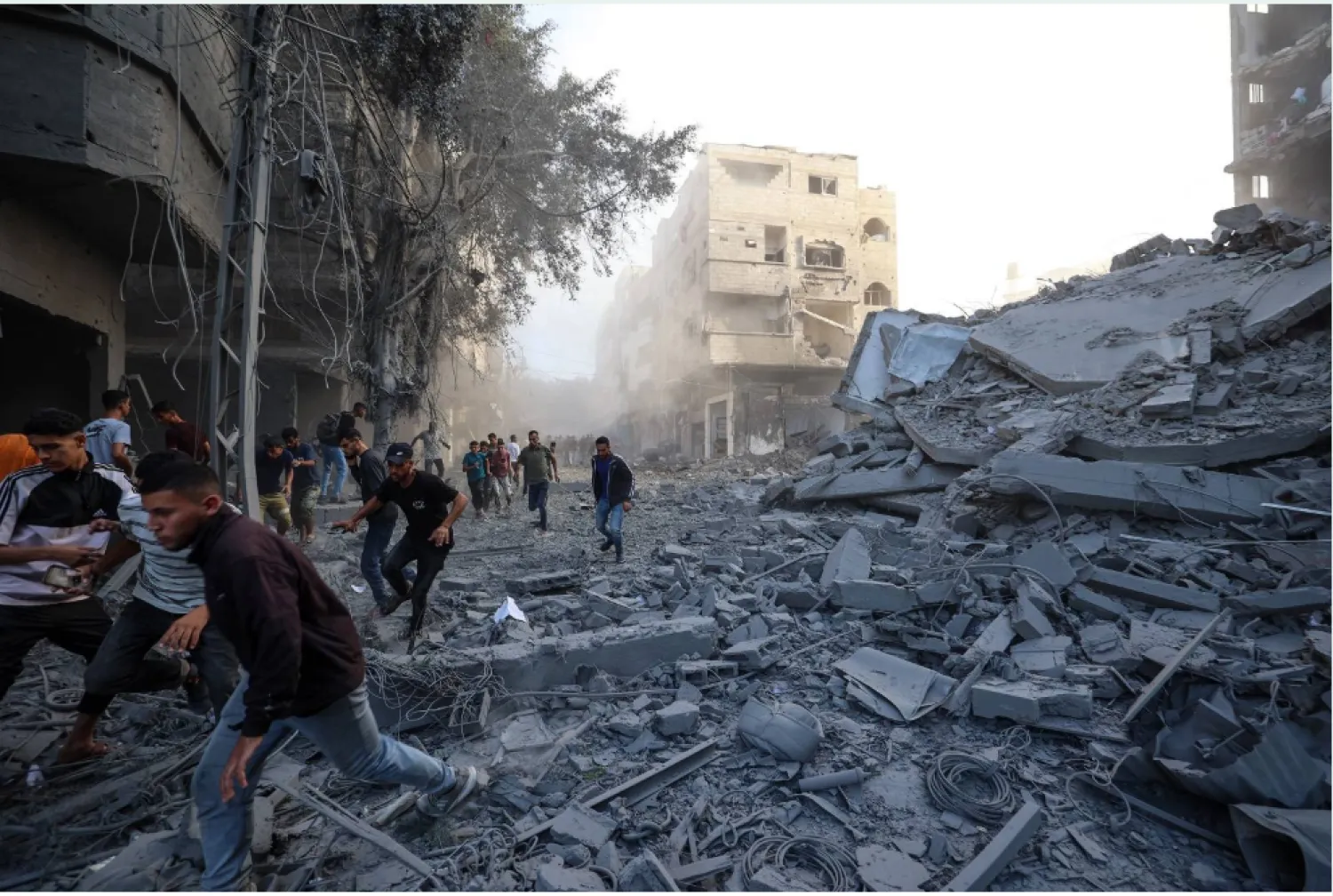 يركض فلسطينيون بحثاً عن ملجأ بعد غارة إسرائيلية استهدفت مبنى في مخيم البريج للاجئين بوسط قطاع غزة (أ.ف.ب)