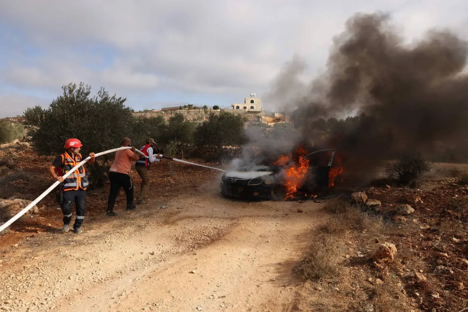 Filistinli itfaiyeciler, 19 Ekim 2025'te Ramallah yakınlarındaki Batı Şeria'daki Turmus Ayya köyünde İsrailli yerleşimciler tarafından ateşe verilen bir araçtaki yangını söndürüyor. (AFP)