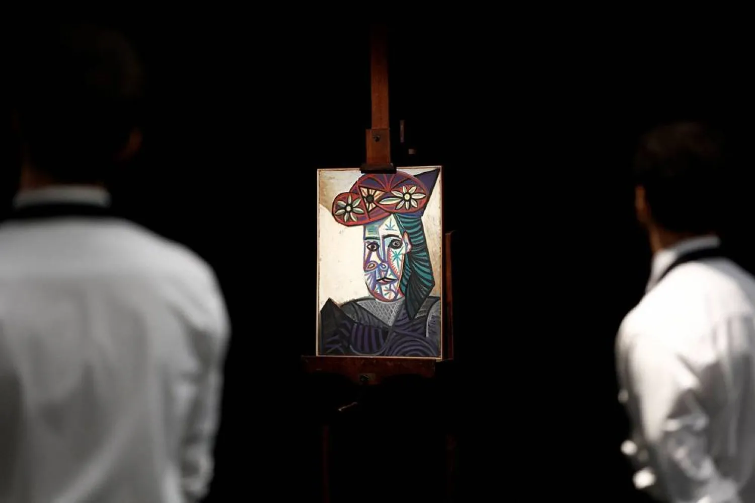 Employees look at the painting "Bust of a Woman with a Flowered Hat (Dora Maar), 1943" (Buste de femme au chapeau a fleurs (Dora Maar), 1943) by Spanish artist Pablo Picasso (1881-1973) on display before its auction at Drouot auction house in Paris, France, September 16, 2025. (Reuters/Benoit Tessier)