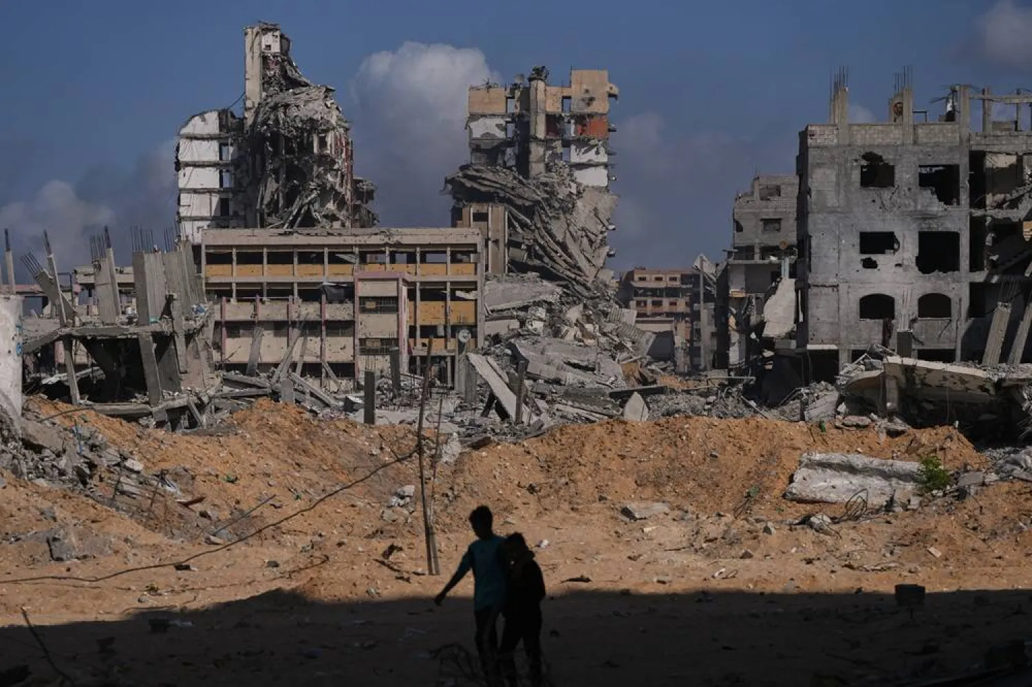  Palestinians walk through the destruction caused by the Israeli air and ground offensive in the Al-Shati camp, in Gaza City, Friday, Oct. 24, 2025. (AP)