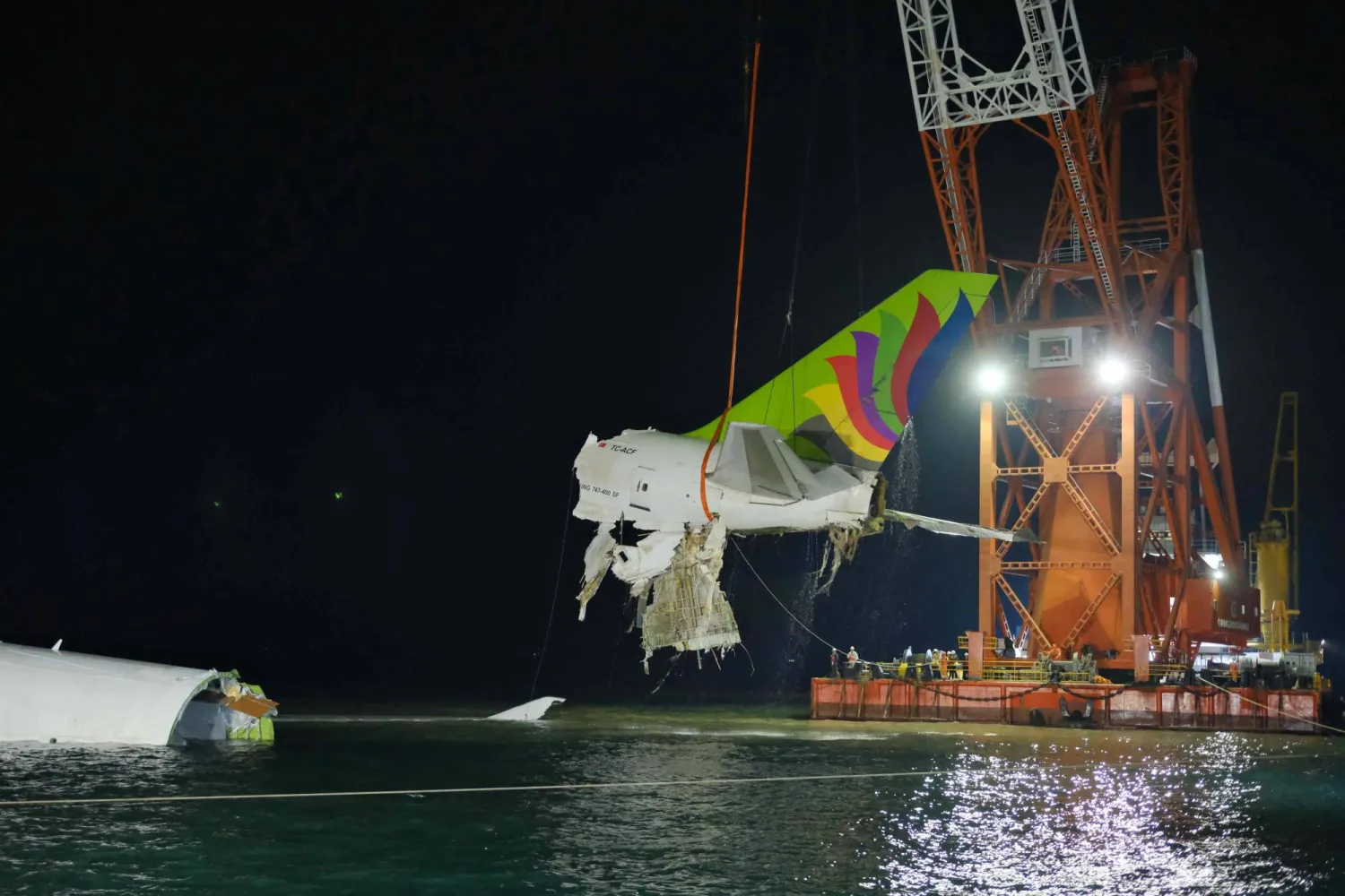This handout photo taken on October 24, 2025 and released on October 25 by Airport Authority Hong Kong shows a crane hoisting the recovered tail section of an ACT Airlines Boeing 747-400 cargo aircraft. (Photo by Handout / Airport Authority Hong Kong / AFP) 