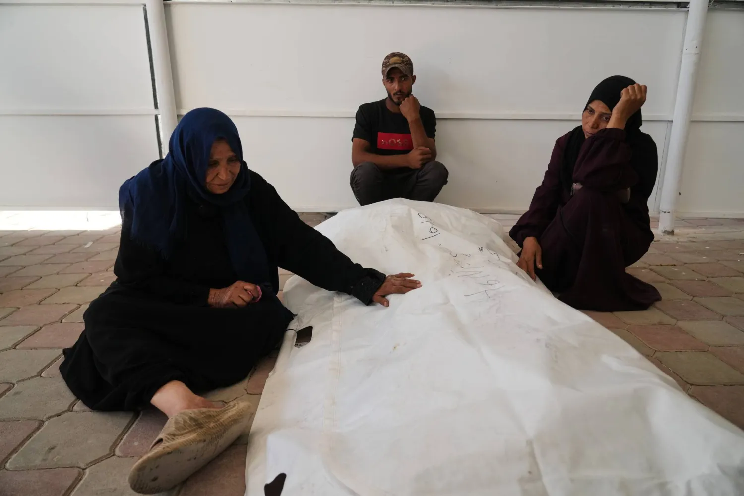 فلسطينية تضع يدها على جثة ابنها بعدما تم التعرف على هويته في «مستشفى ناصر» بخان يونس في 18 أكتوبر 2025 (أ.ب)