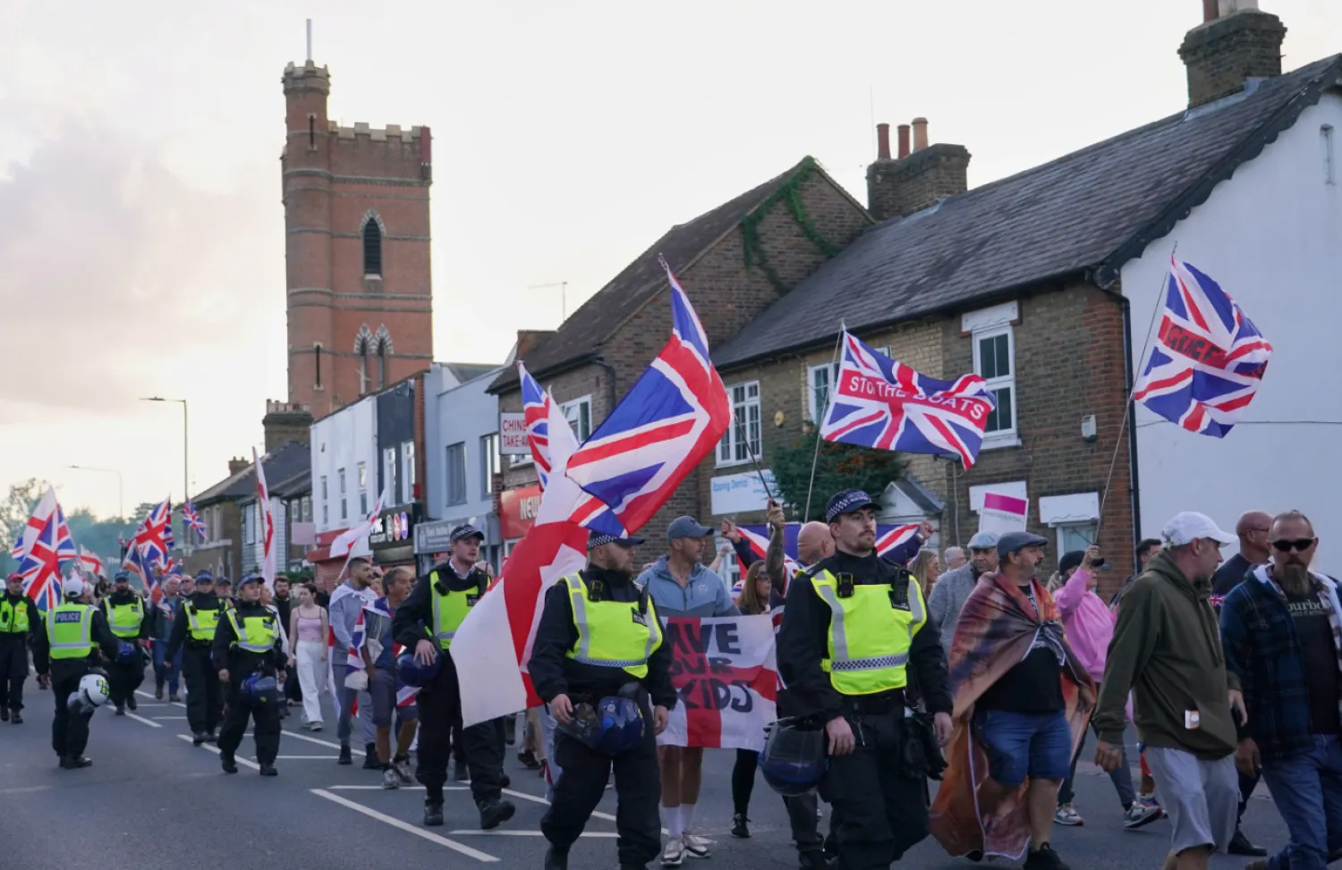 Police officers escort protesters near the Bell Hotel in Epping, London, Sunday, Aug. 31, 2025 after a temporary injunction that would have blocked asylum seekers from being housed at the hotel was overturned. (AP Photo/Alberto Pezzali, File)