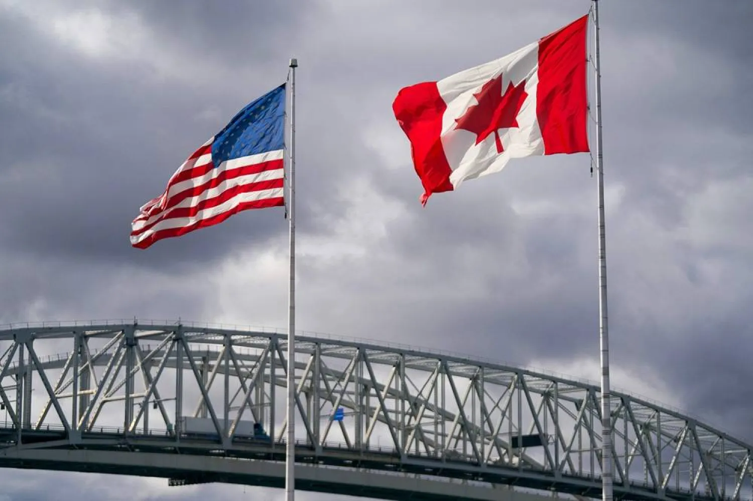 The US and Canada flags flutter next to the Blue Water Bridge border crossing in Point Edward, Ontario, on October 24, 2025. (AFP) 