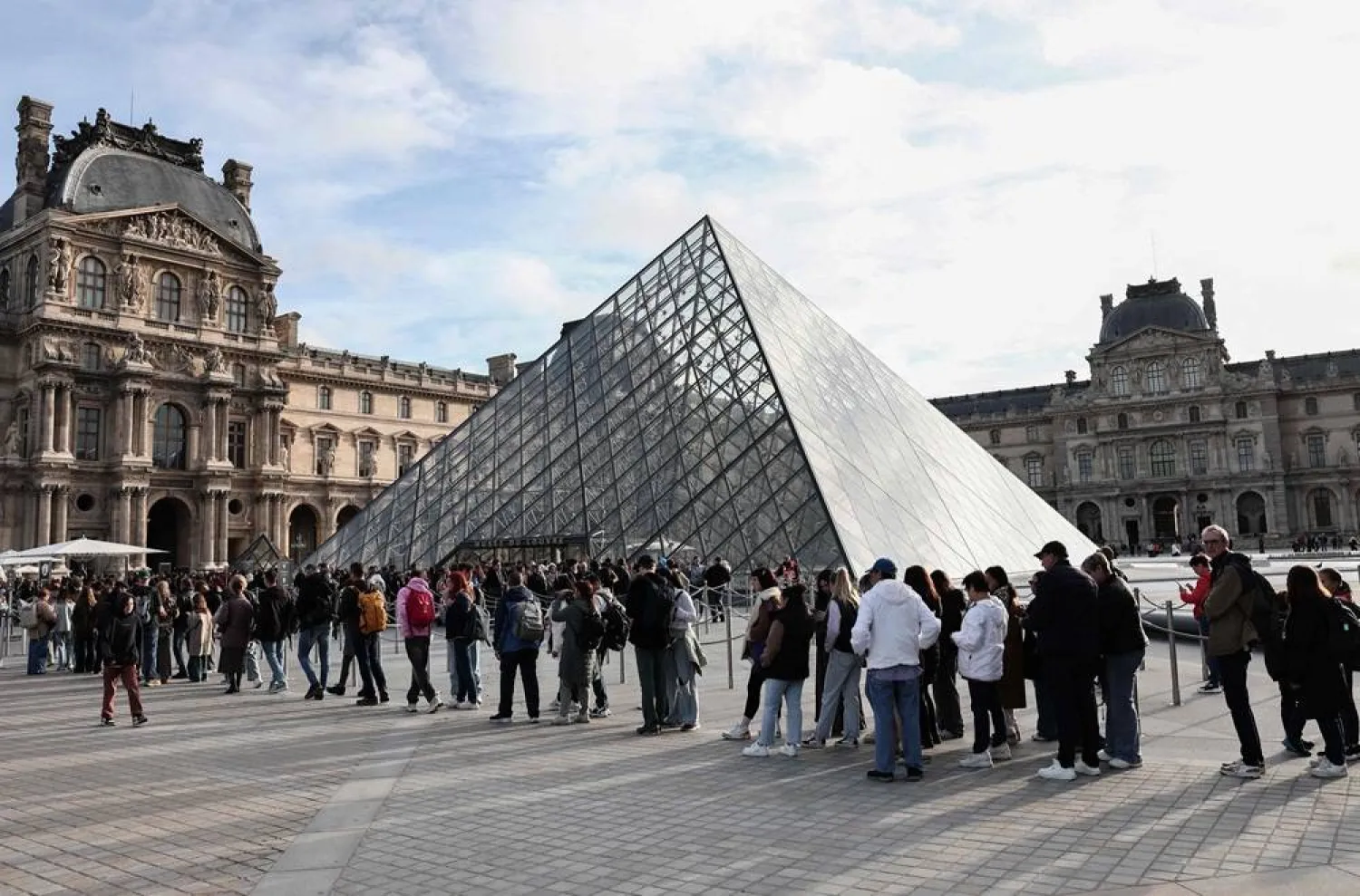Visitors queue in front of the Pyramide du Louvre, designed by Chinese-US architect Ieoh Ming Pei, with the Louvre Museum in the background in Paris on October 22, 2025. (AFP)