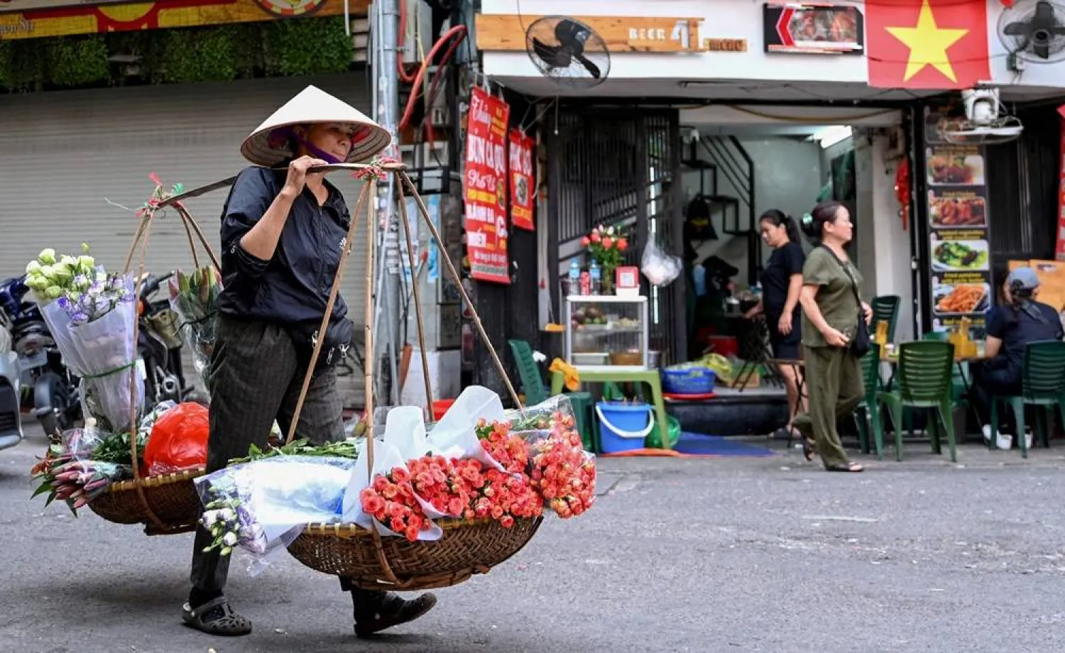 A street vendor carries bouquets of flowers for sale in Hanoi on October 22, 2025. (AFP)