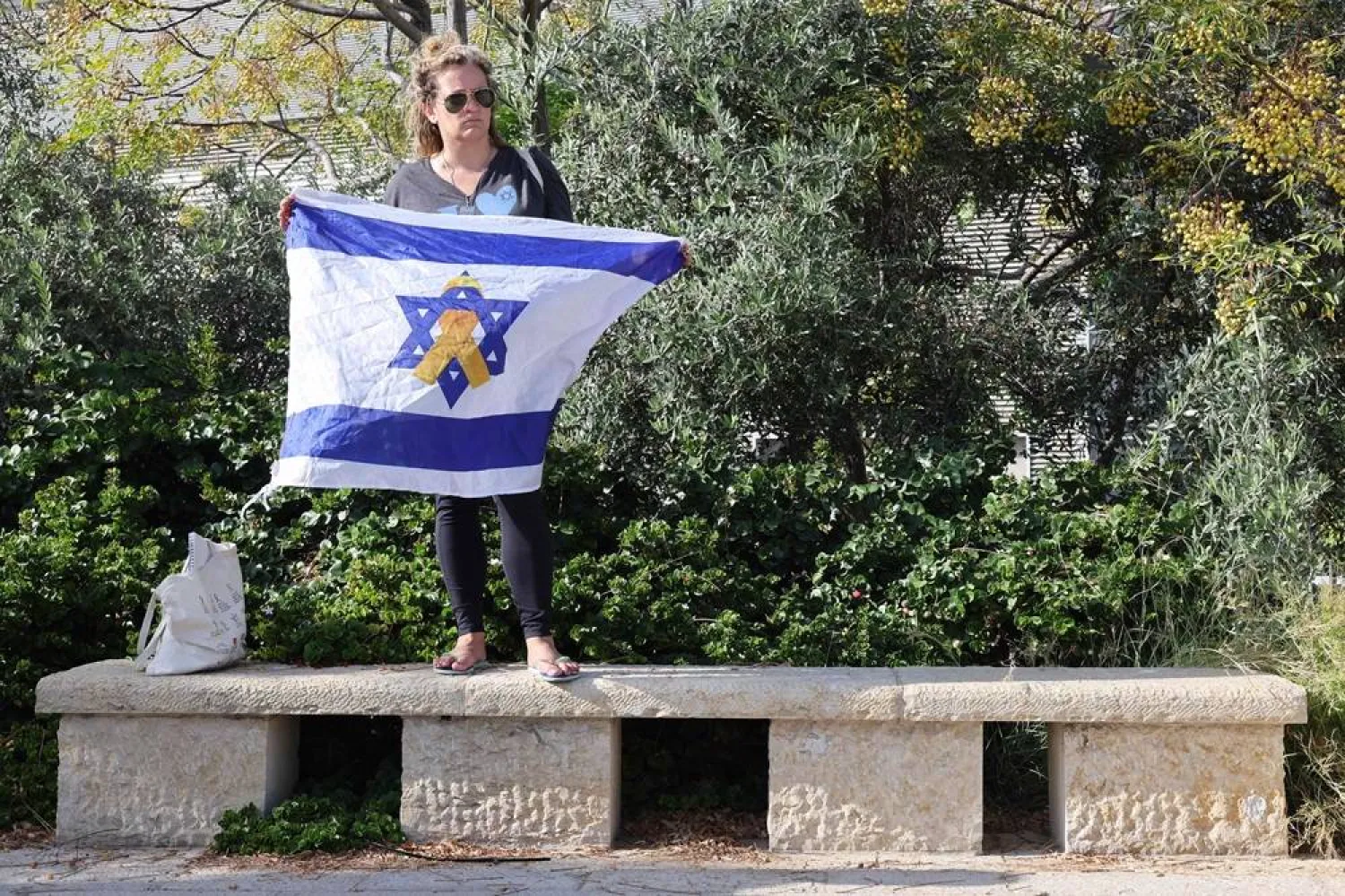 A woman carries the Israeli flag during a farewell ceremony for Thai national Sonthaya Oakkharasri, who killed in the October 7, 2023, attack by Hamas, at the Ben Gurion Airport in Tel Aviv on October 22, 2025, ahead of his flight back to Thailand. (AFP) 