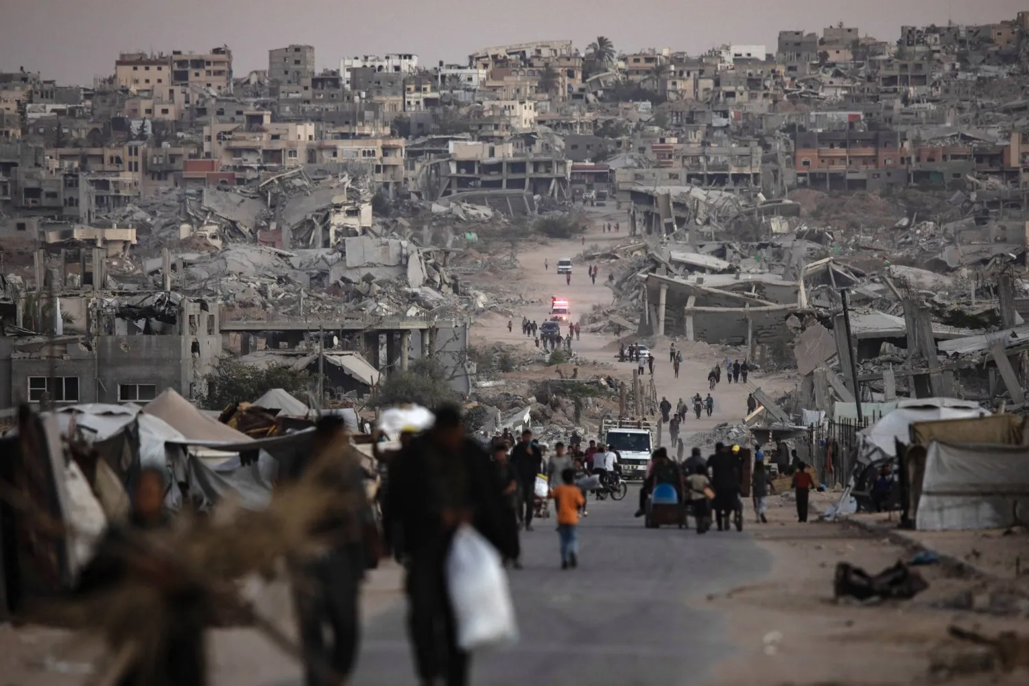 فلسطينيون يسيرون بين أنقاض منازلهم المدمَّرة في خان يونس بجنوب قطاع غزة (إ.ب.أ)