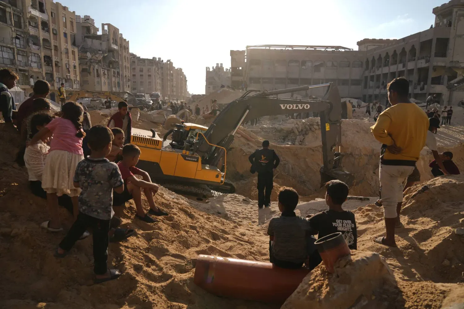 Dün Gazze Şeridi'nin güneyindeki Han Yunus'ta İsrailli rehinelerin cesetlerini aramak için Mısırlı bir ekibin yürüttüğü kazıları inceleyen Filistinliler (AP)