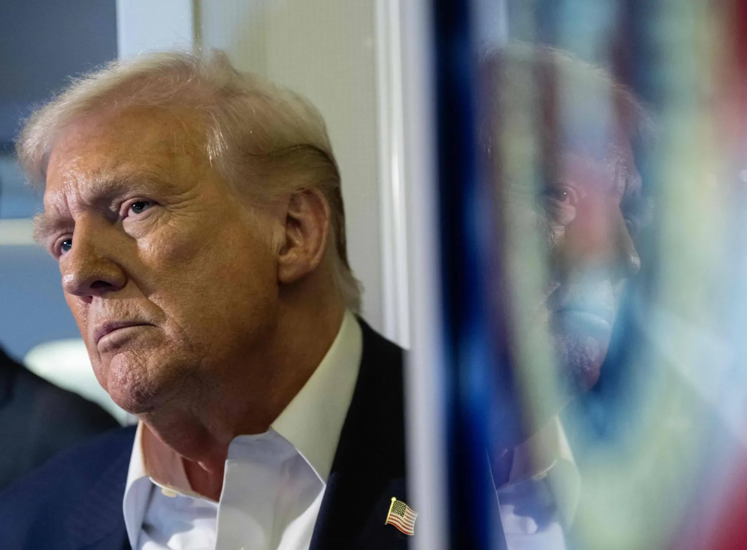 US President Donald Trump is reflected in a monitor as he speaks to the media aboard Air Force One as he flies to Japan on October 27, 2025. (Photo by ANDREW CABALLERO-REYNOLDS / AFP)
