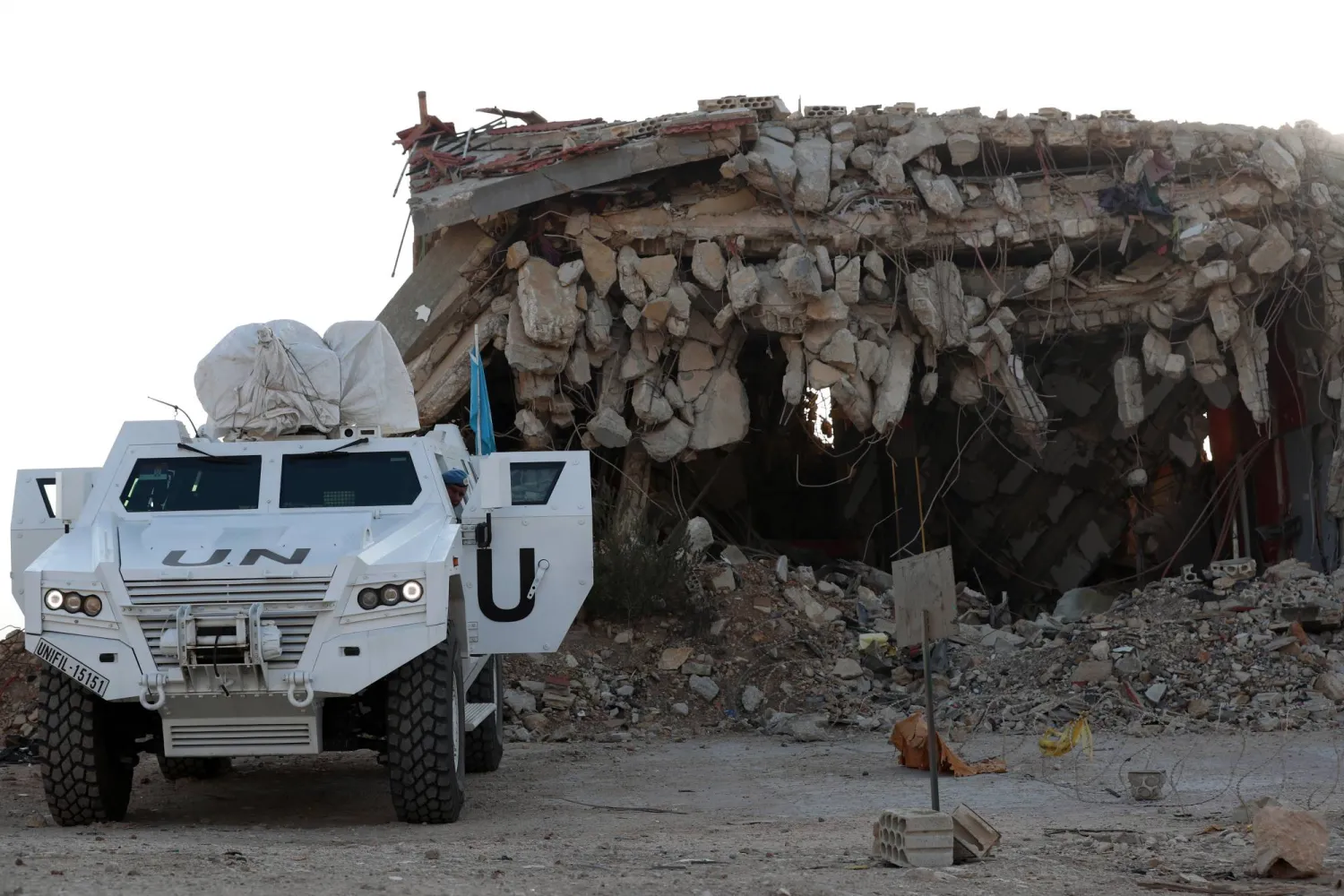 آلية لـ«اليونيفيل» تقف إلى جانب مبنى مدمر في بلدة العديسة الحدودية مع إسرائيل بجنوب لبنان (إ.ب.أ)