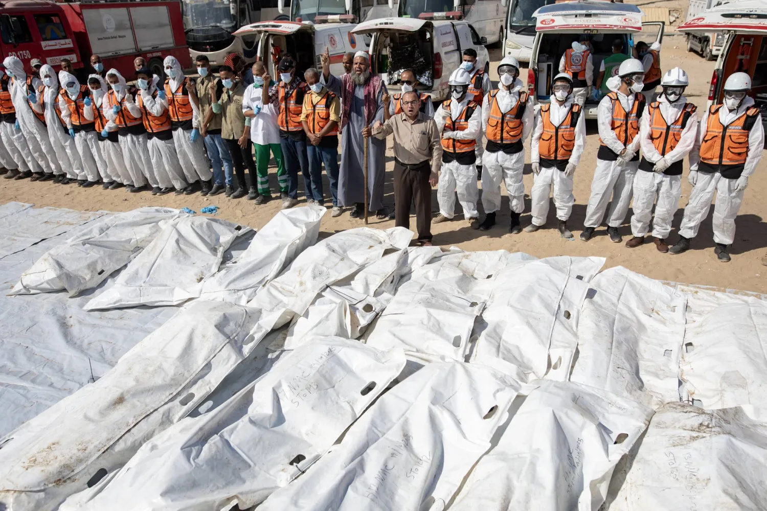 أفراد من فرق البحث والإنقاذ يصلون أمام جثامين فلسطينيين مجهولي الهوية أمام مجمع ناصر الطبي في خان يونس يوم الاثنين بعدما سلمتها إسرائيل (إ.ب.أ)