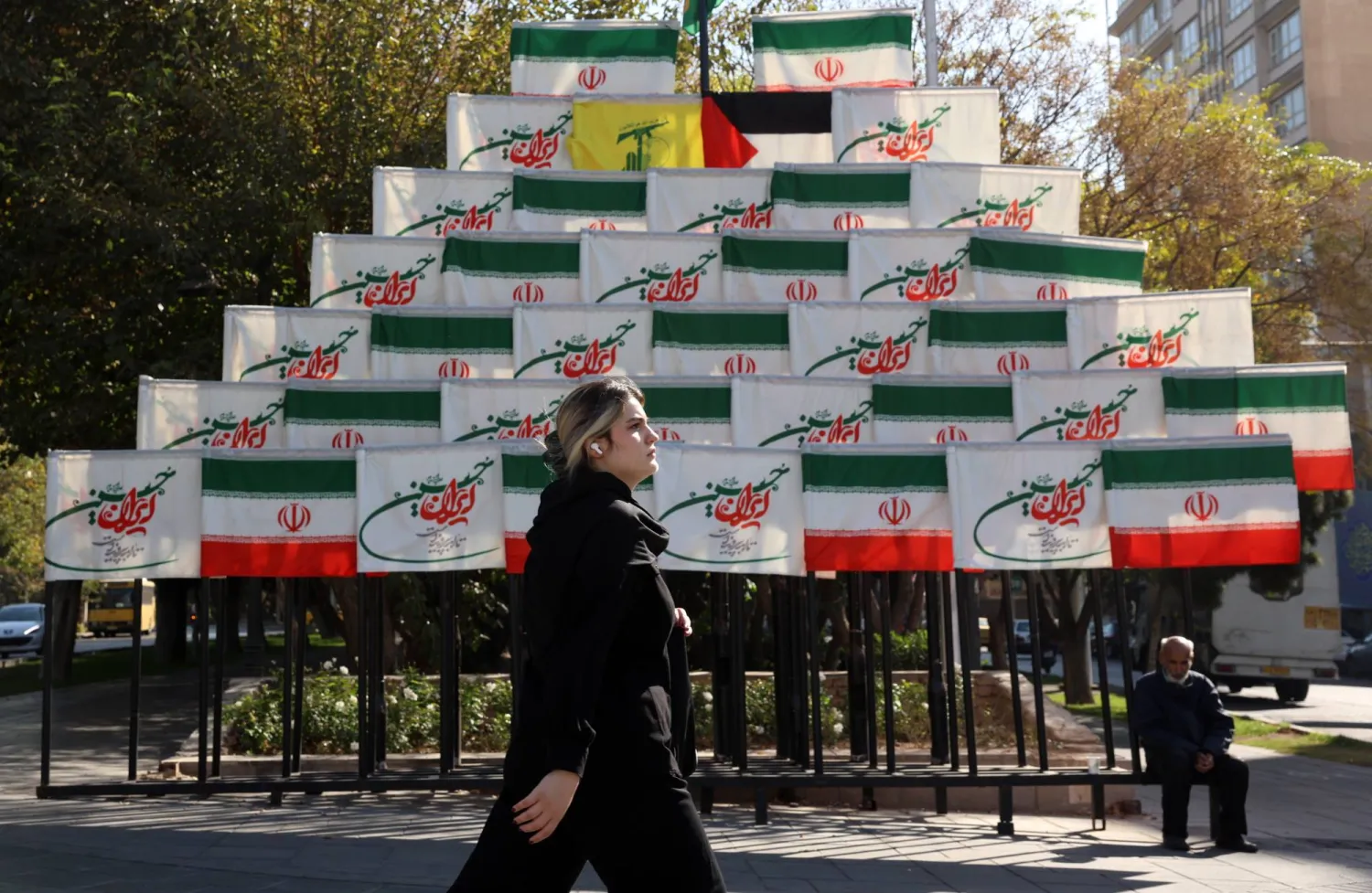 امرأة إيرانية تمر بجانب أعلام معروضة في أحد شوارع طهران الاثنين (إ.ب.أ)