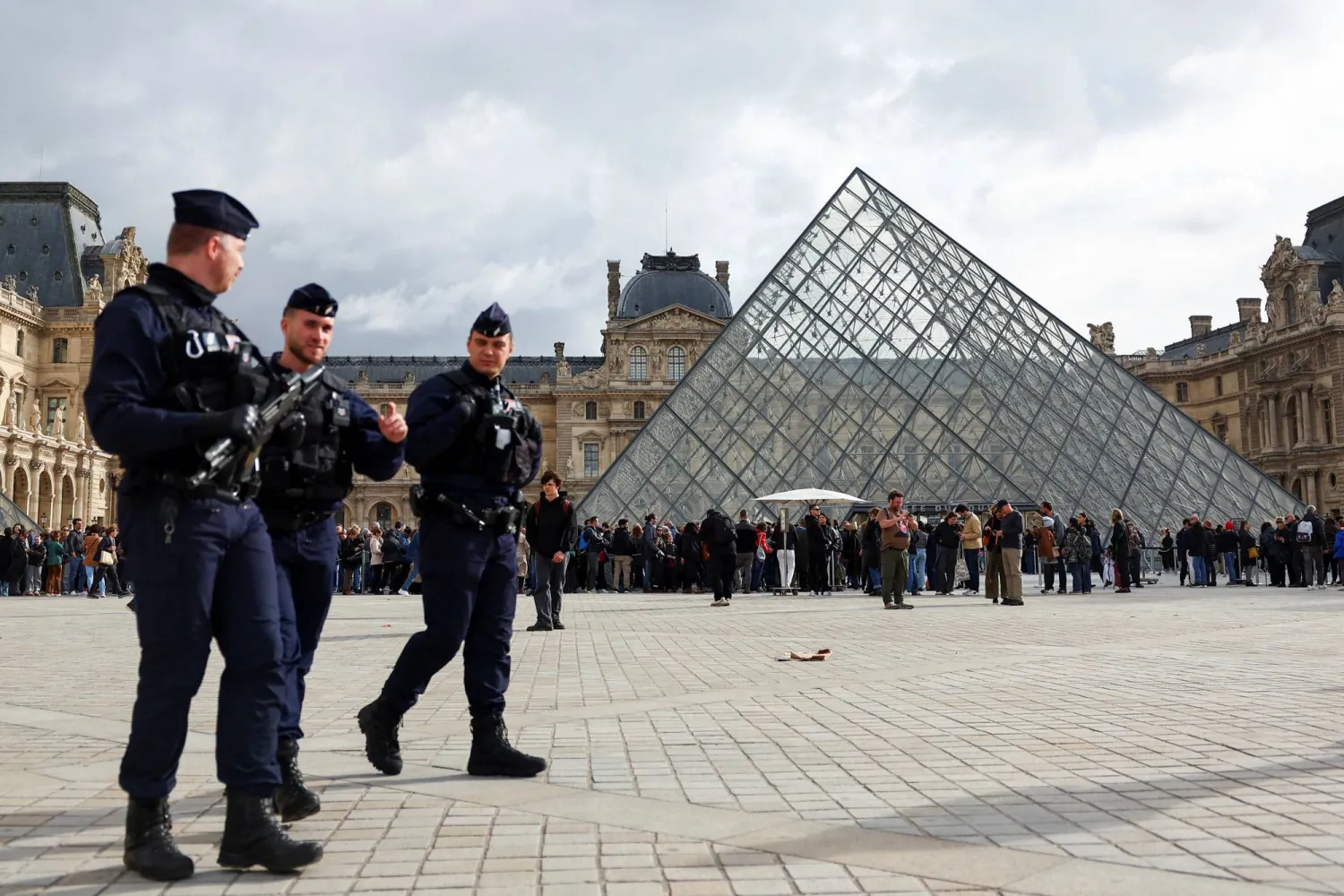  French CRS riot police officers walk near the glass Pyramid of the Louvre Museum, after French police arrested suspects in the Louvre heist case, in Paris, France October 27, 2025. (Reuters)