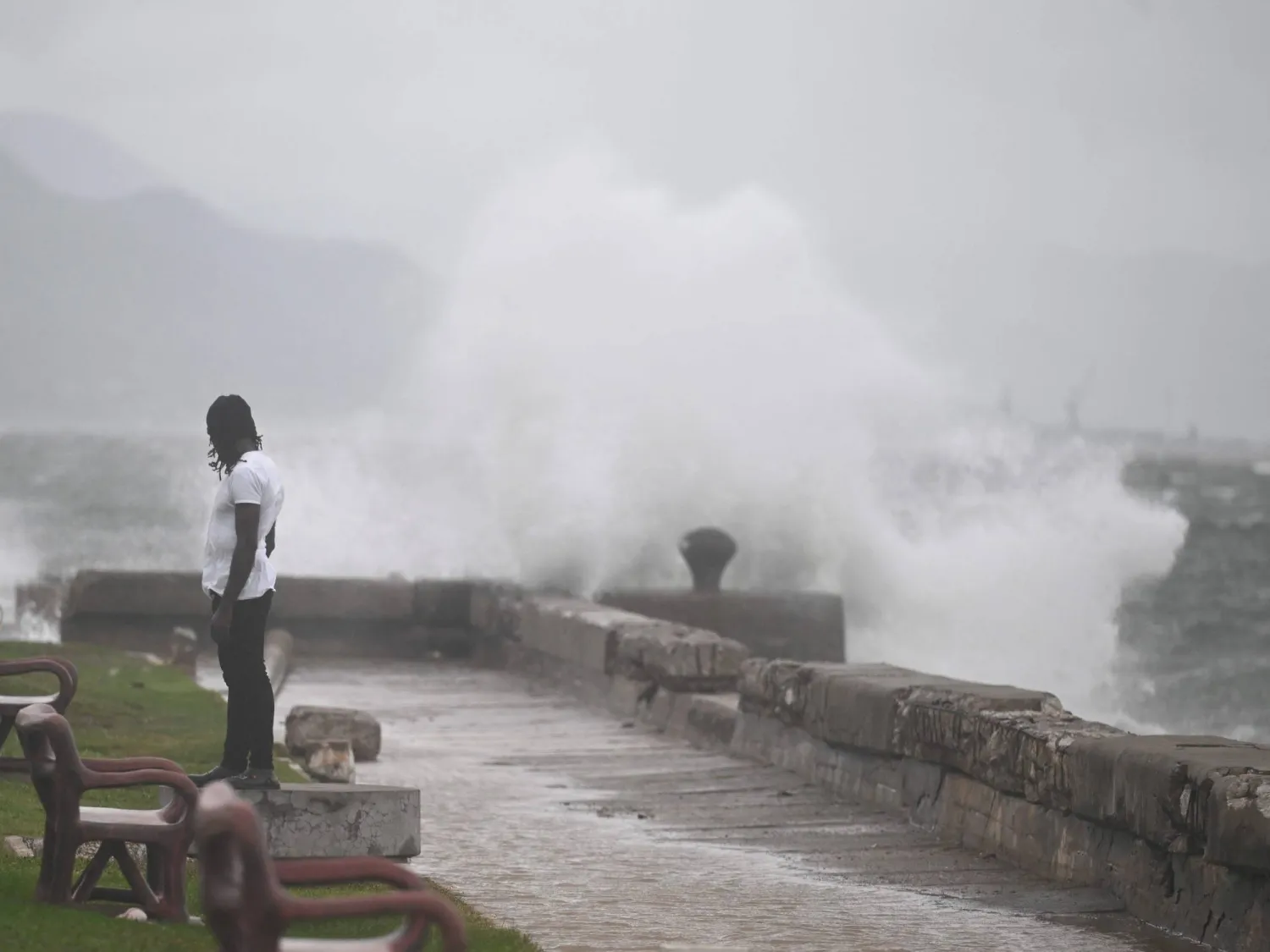 A man watches the waves crash into the walls at the Kingston Waterfront on October 27, 2025. (Photo by Ricardo Makyn / AFP)