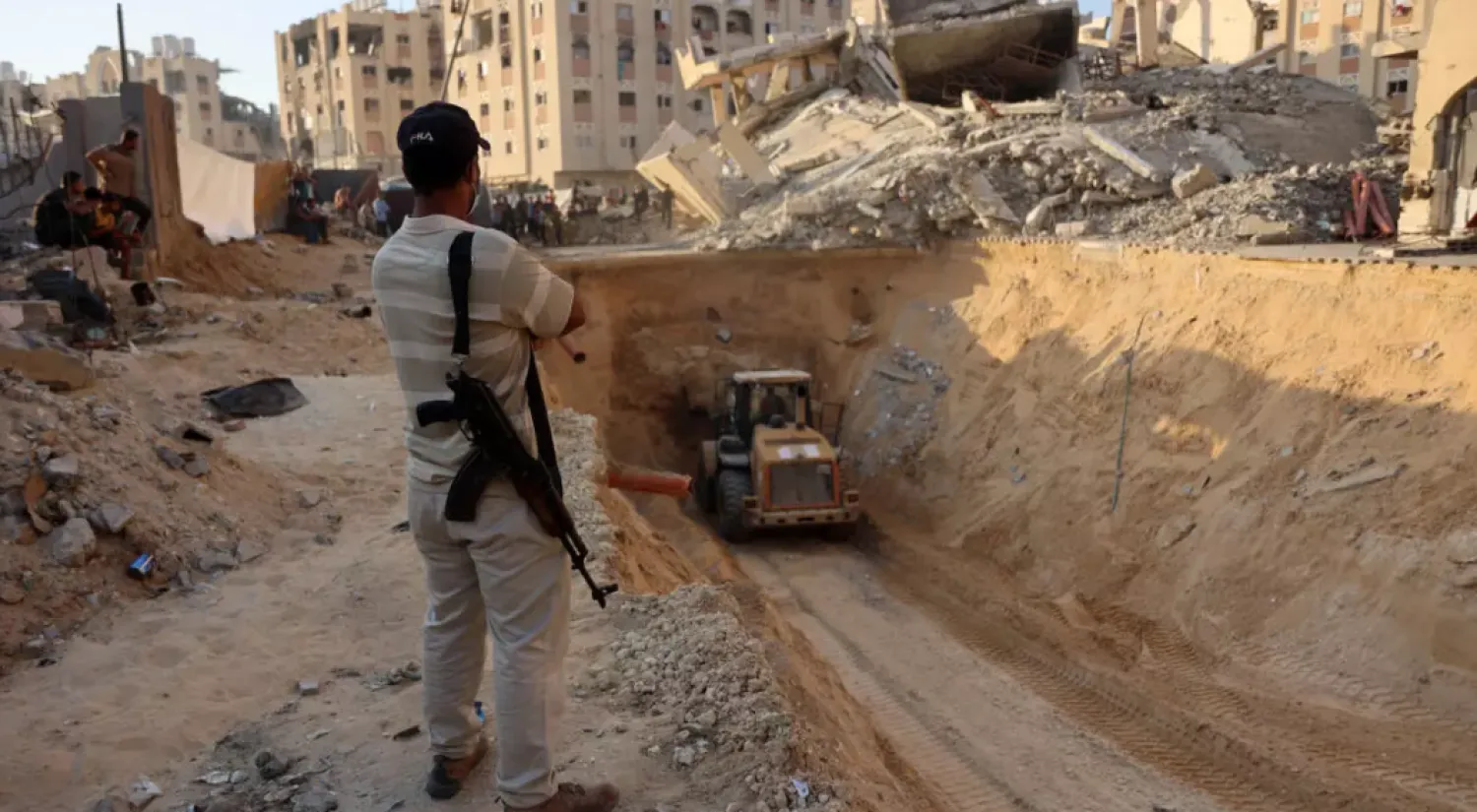 FILE: An armed Palestinian man looks at an excavator reportedly digging for the bodies of Israeli hostages © Omar AL-QATTAA / AFP
