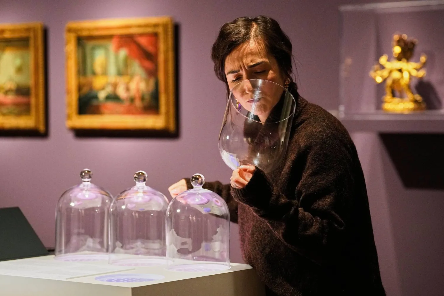 A woman smells samples during the exhibition "The Secret Power of Scents", showing the history of scent from antiquity to the present as a sensory experience at the Kunstpalast art museum in Duesseldorf, Germany, Tuesday, Oct. 28, 2025. (AP)