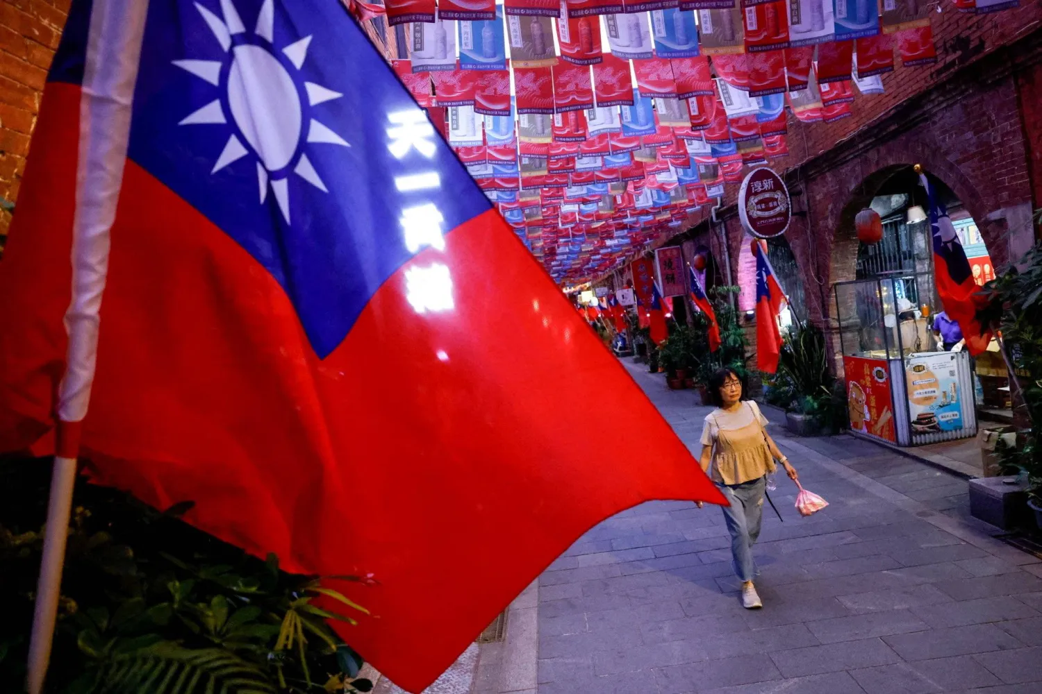 A woman walks past a street lined with Taiwanese flags, in Kinmen, Taiwan, October 19, 2025. (Reuters)