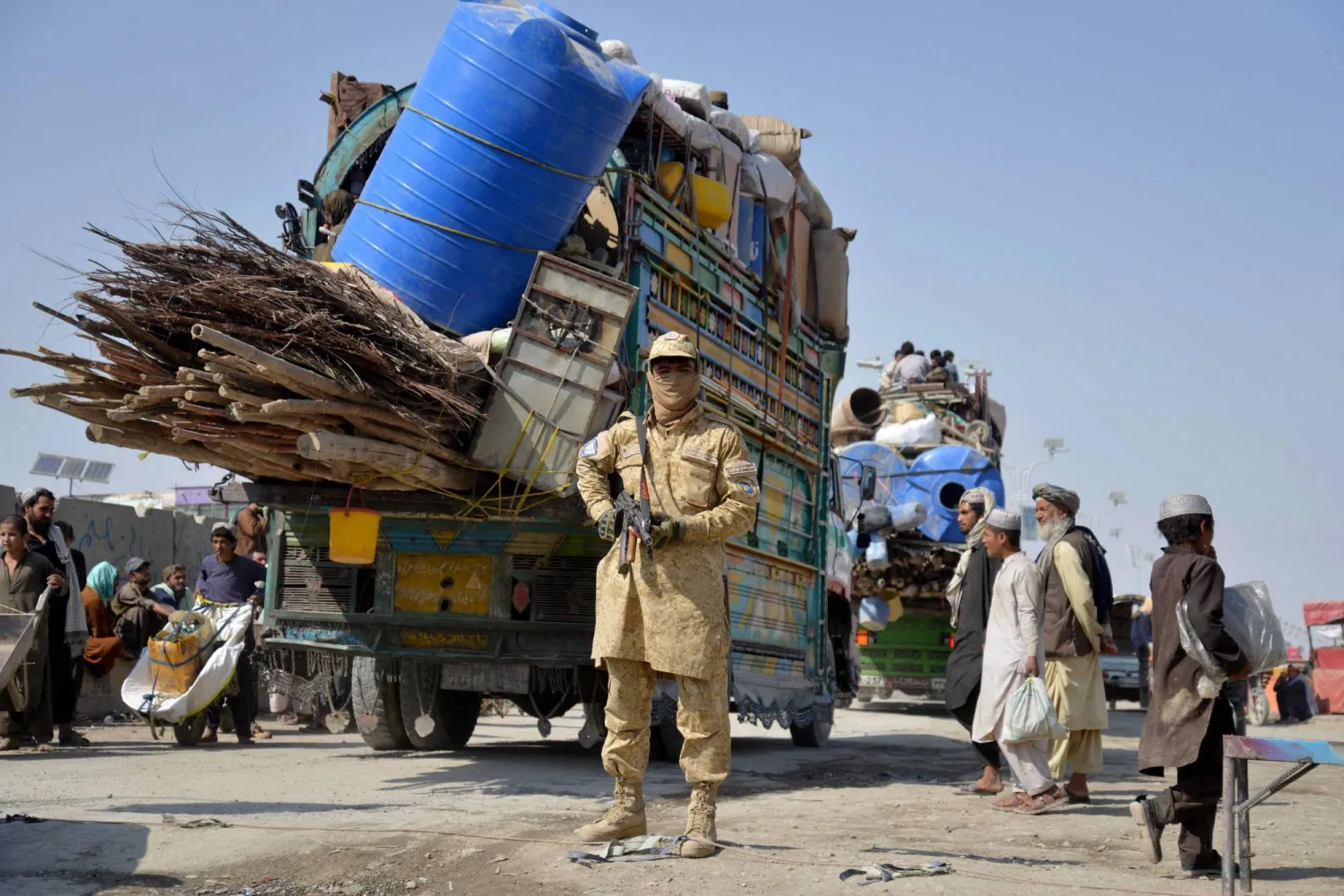 A Taliban security personnel stands guard as deported Afghan refugees from Pakistan arrive at the zero-point border crossing between Afghanistan and Pakistan, in the Spin Boldak district of Kandahar province on October 27, 2025. (AFP)