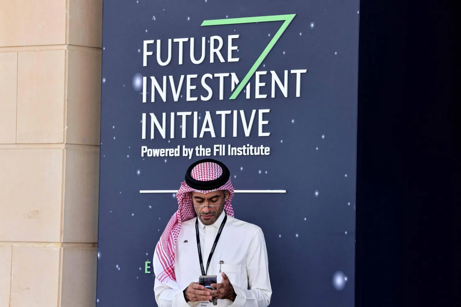 A Saudi man looks at his mobile phone as he attends the opening ceremony of the Future Investment Initiative, in Riyadh on October 28, 2025. (AFP)