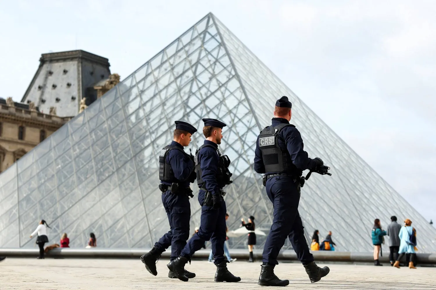 French CRS riot police officers walk near the glass Pyramid of the Louvre Museum, after French police arrested suspects in the Louvre heist case, in Paris, France October 27, 2025. (Reuters)