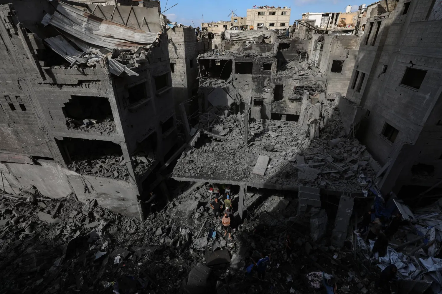 فلسطينيون يفحصون الدمار بين أنقاض المنازل المدمرة إثر غارة جوية إسرائيلية استهدفت مبنى سكني في مخيم الشاطئ للاجئين بمدينة غزة (إ.ب.أ)