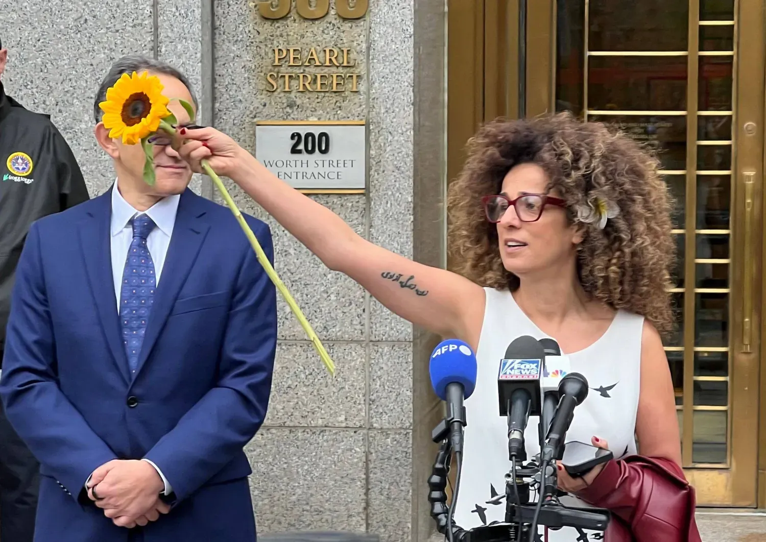 İran asıllı Amerikalı gazeteci Masih Alinejad, kararın ardından adliye binasının dışında çiçek uzatıyor (AFP)