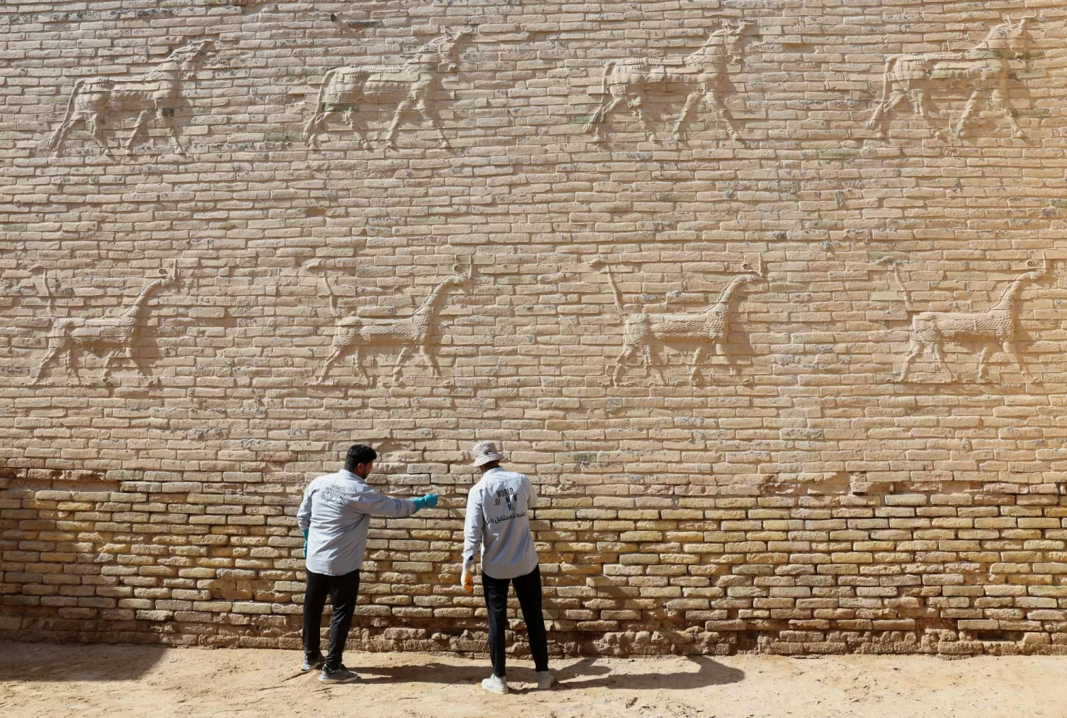 Workers clean salt deposits from a wall decorated with animal reliefs at Babylon, a UNESCO World Heritage site, in Babylon, Iraq, October 22, 2025. REUTERS/Ahmed Saad