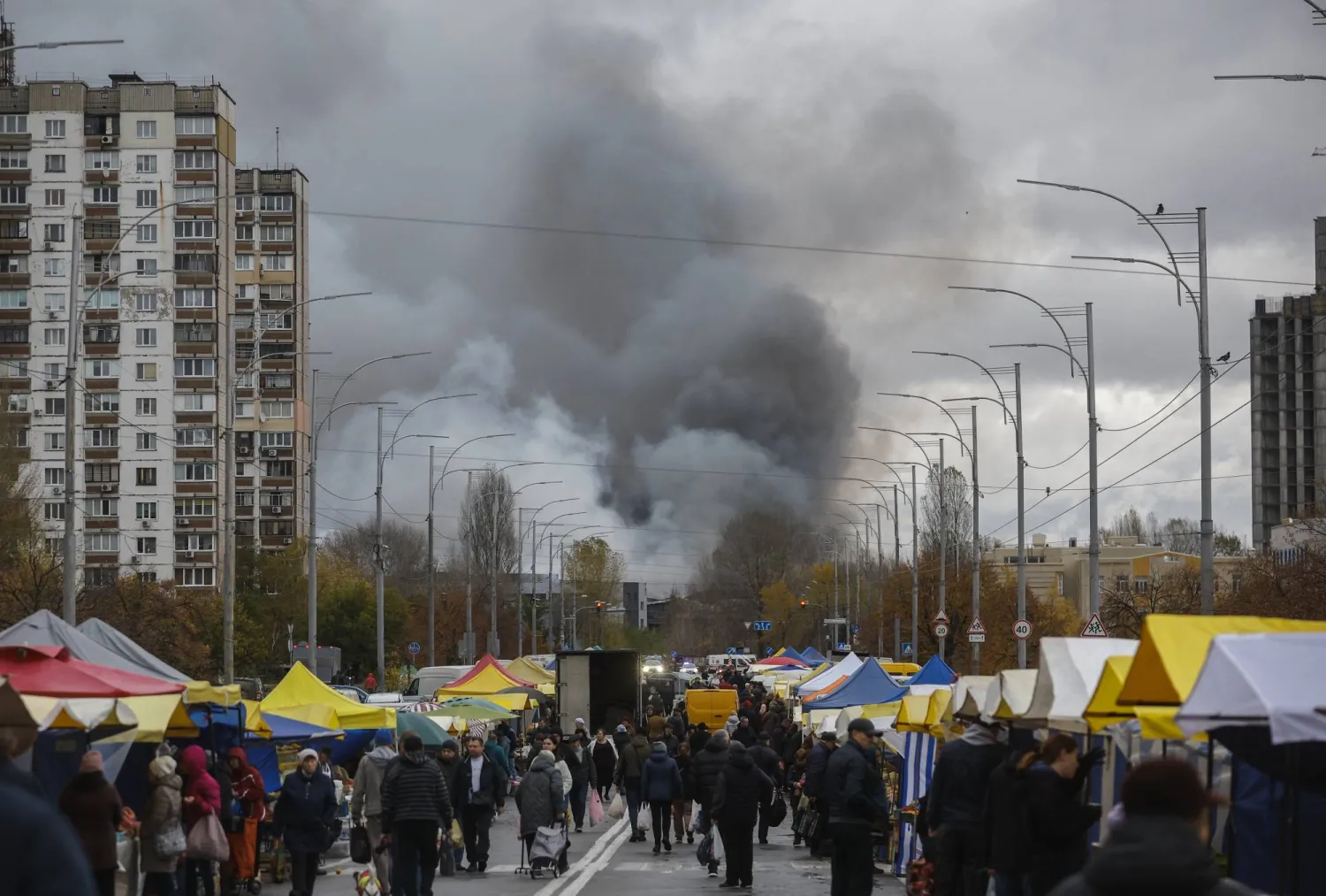 سكان يتجمّعون في منطقة سكنية بينما تشتعل النيران بمبنى بعد ضربات روسية على كييف (إ.ب.أ)