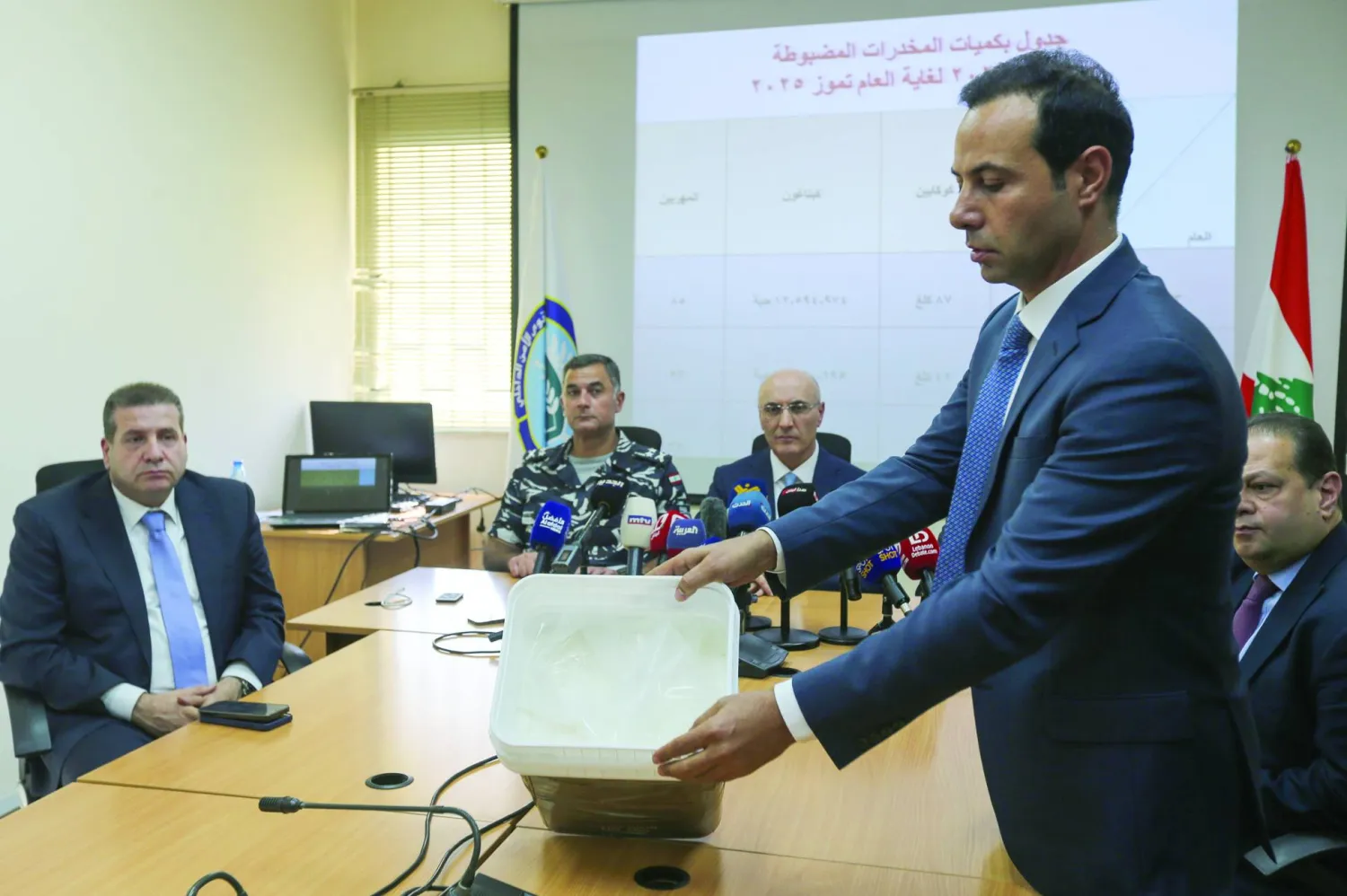 عنصر في مكتب مكافحة المخدرات في لبنان يعرض مخدرات مخبأة في «غالون» حيث أحبط تهريبها الشهر الماضي (إ.ب.أ) 