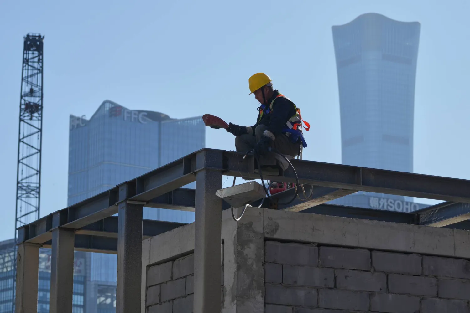 A worker takes a rest on a construction site near the capital's tallest skyscraper China Zun Tower and other office buildings at the central business district, in Beijing, Monday, Oct. 27, 2025. (AP)