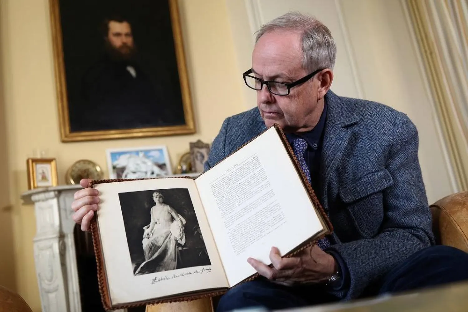 Count of Paris Jean d'Orleans, Head of the Royal House of France, whose grandmother and great grandmother wore the jewels stolen from the Louvre Museum, holds a book with a photo of his great grandmother Marie-Isabelle d'Orleans, during an interview with Reuters in his house next to the Royal Chapel of Dreux, France, October 30, 2025. (Reuters) 