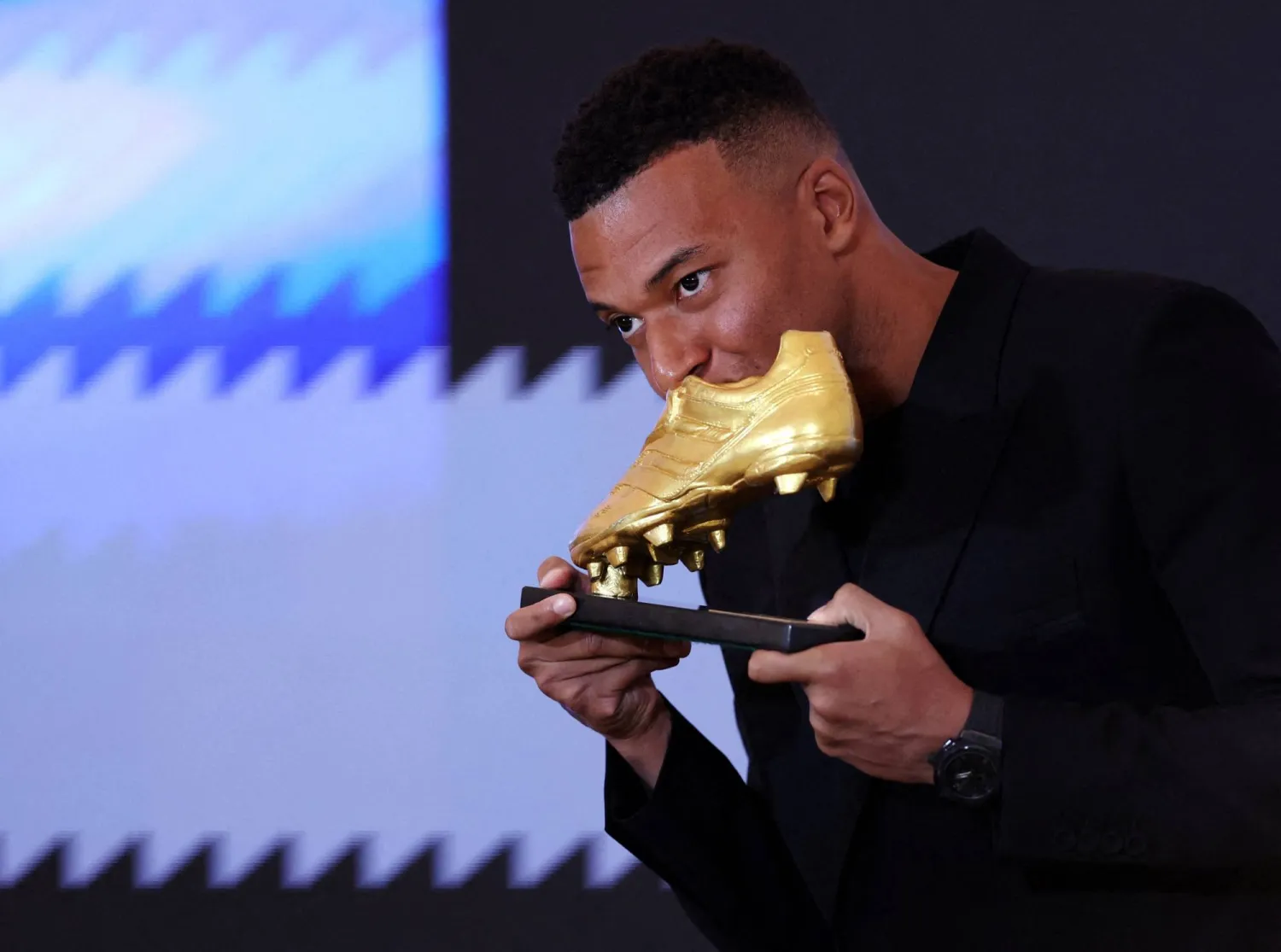 مبابي يُقبّل الجائزة لحظة تسلمه إياها (رويترز)