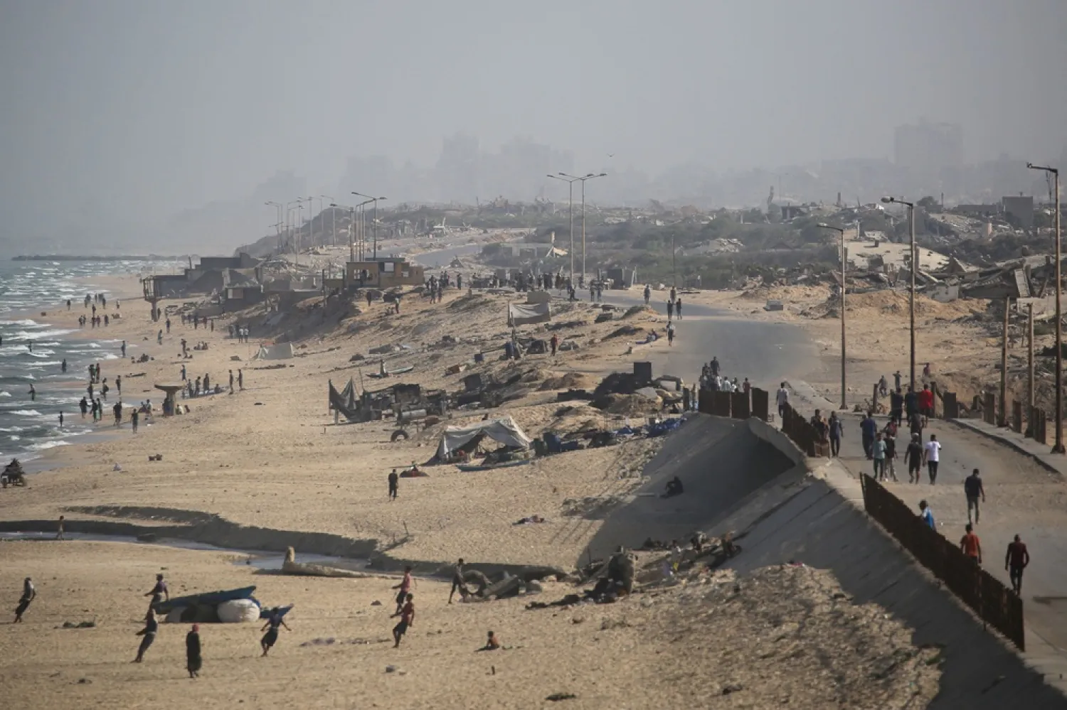 Palestinians walk on a coastal path northwest of Nuseirat refugee camp as they are displaced southward following an Israeli announcement of closing Al-Rashid road towards the north of the besieged Gaza Strip on October 4, 2025. (AFP)