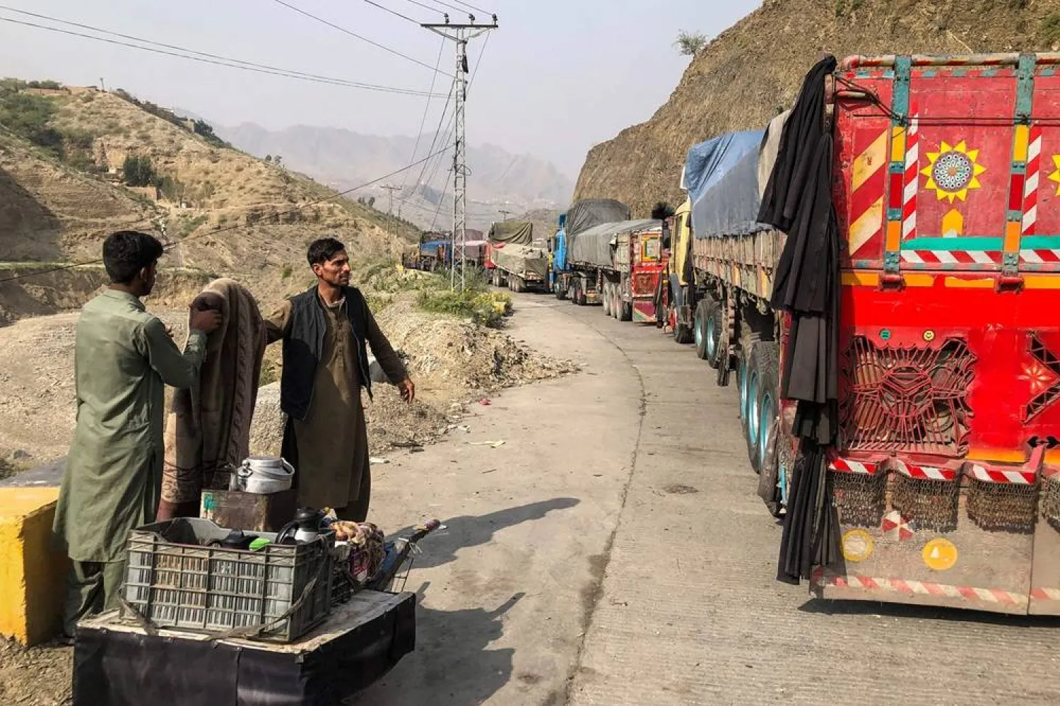 A tea vendor stands near the stalled vehicles near the closed Pakistan-Afghanistan border town of Torkham on October 19, 2025, after cross-border clashes between the two countries. (AFP) 