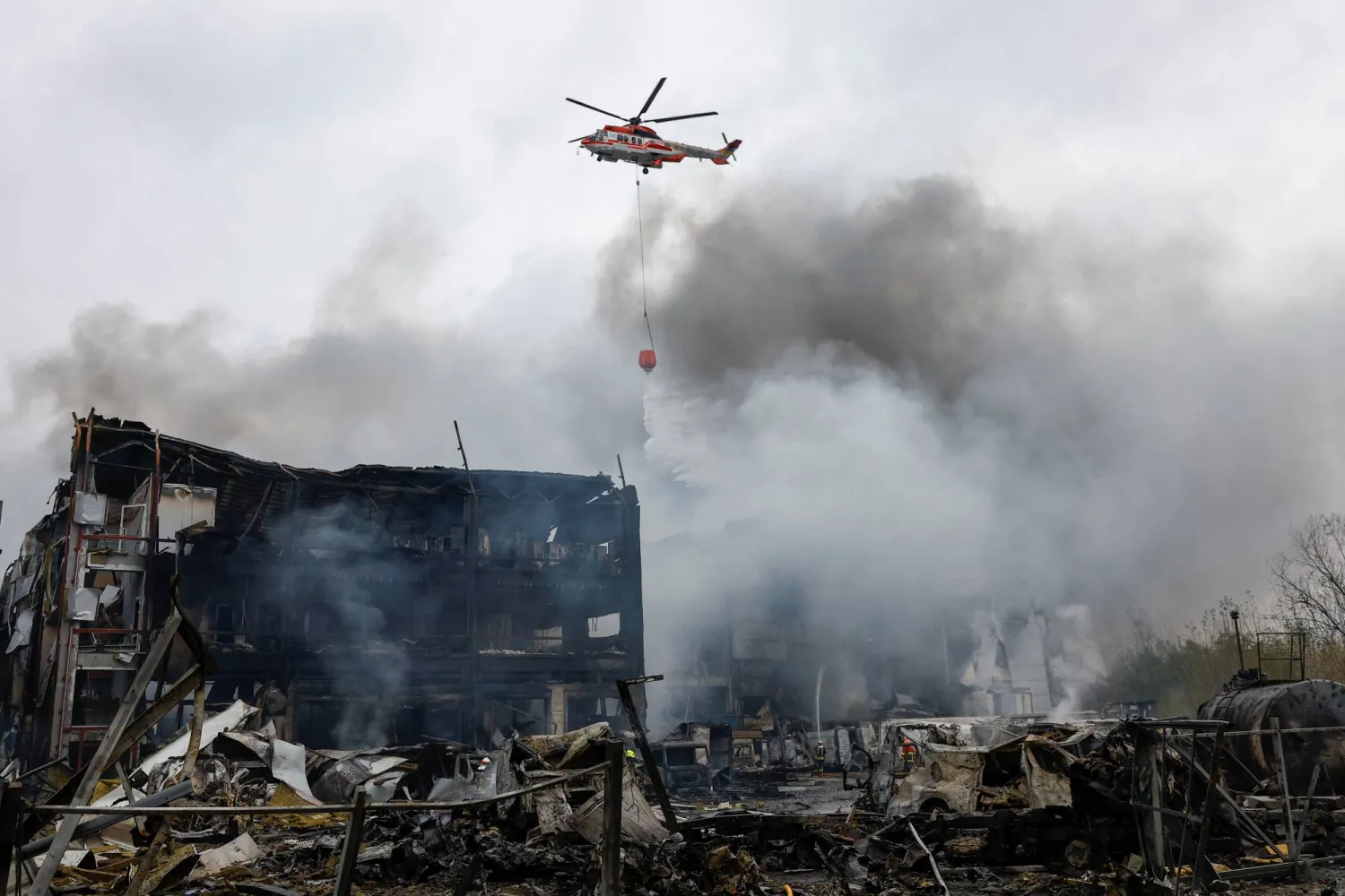 هليكوبتر تسقط المياه على مستودعات الأغذية التي تعرضت لقصف صاروخي روسي في كييف (رويترز)