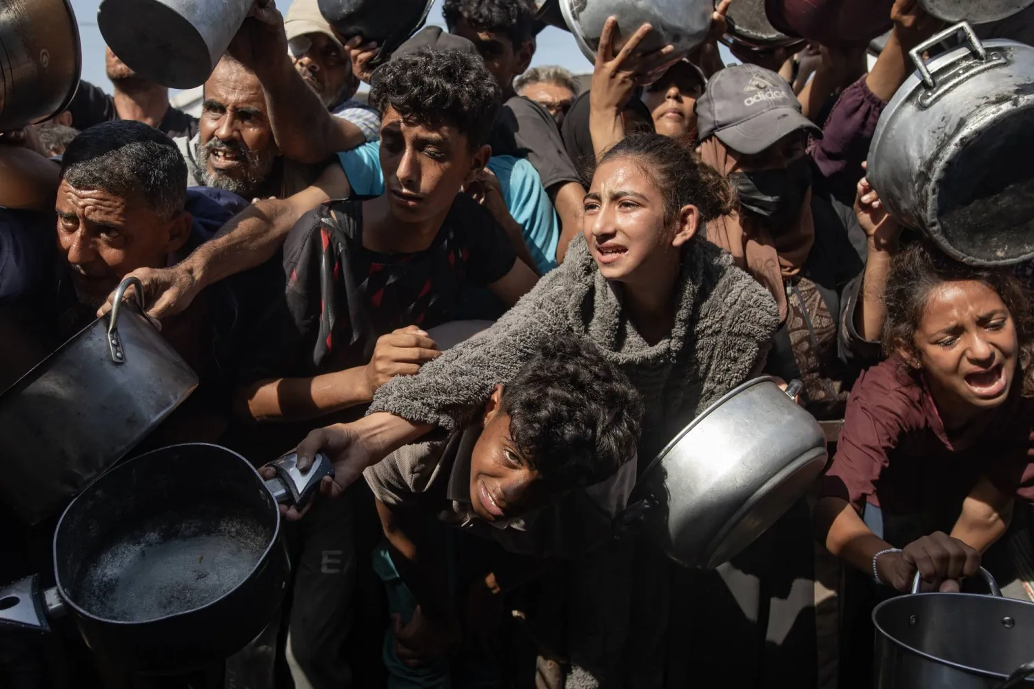 نازحون فلسطينيون يحاولون الحصول على وجبة طعام من مطبخ خيري في خان يونس جنوب قطاع غزة الجمعة (إ.ب.أ)
