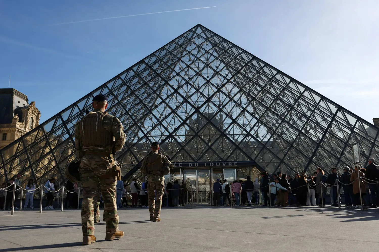 French soldiers from the "Sentinelle" security plan patrol past the glass Pyramid while people queue to enter the Louvre Museum as French police have arrested more suspects linked to the theft of treasures from the Louvre museum's Galerie d'Apollon (Apollo gallery), in Paris, France, October 30, 2025. (Reuters)