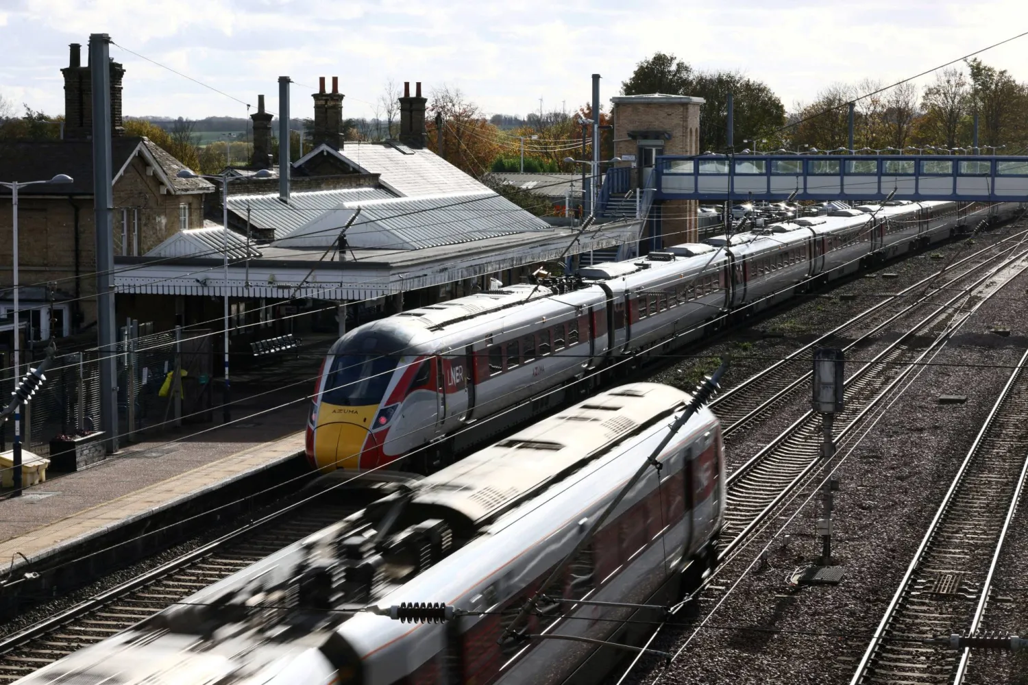 A train passes through Huntingdon Station, as the London North Eastern Railway (LNER) train, where a series of stabbings took place, remains on the platform, near Cambridge, Britain, November 2, 2025. REUTERS/Jack Taylor