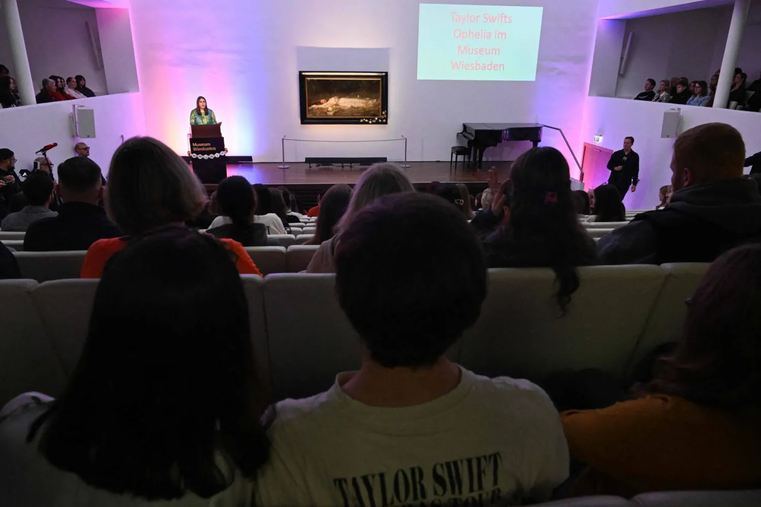 Fans of US singer-songwriter Taylor Swift and other visitors listen to a lecture about the painting 'Ophelia' (ca 1900) by German artist Friedrich Heyser during a short guided tour at the Museum in Wiesbaden, western Germany on November 2, 2025. (Photo by Kirill KUDRYAVTSEV / AFP) 