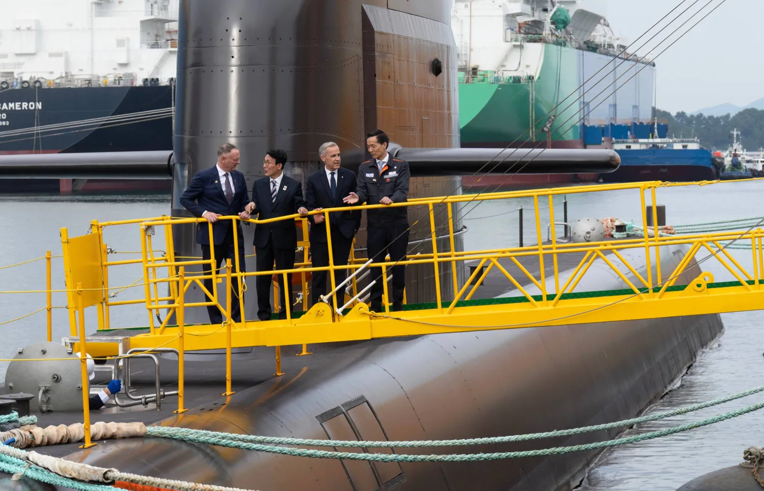 From left, Canadian National Defense Minister David McGuinty, South Korea Prime Minister Kim Min-seok, Canadian Prime Minister Mark Carney and Hahnwa Group Vice-Chairman Kim Dong Kwan speak amongst themselves after touring a submarine at the Hanwha Ocean Shipyard in Geoje Island, South Korea, Thursday Oct. 30, 2025. (Adrian Wyld/The Canadian Press via AP)