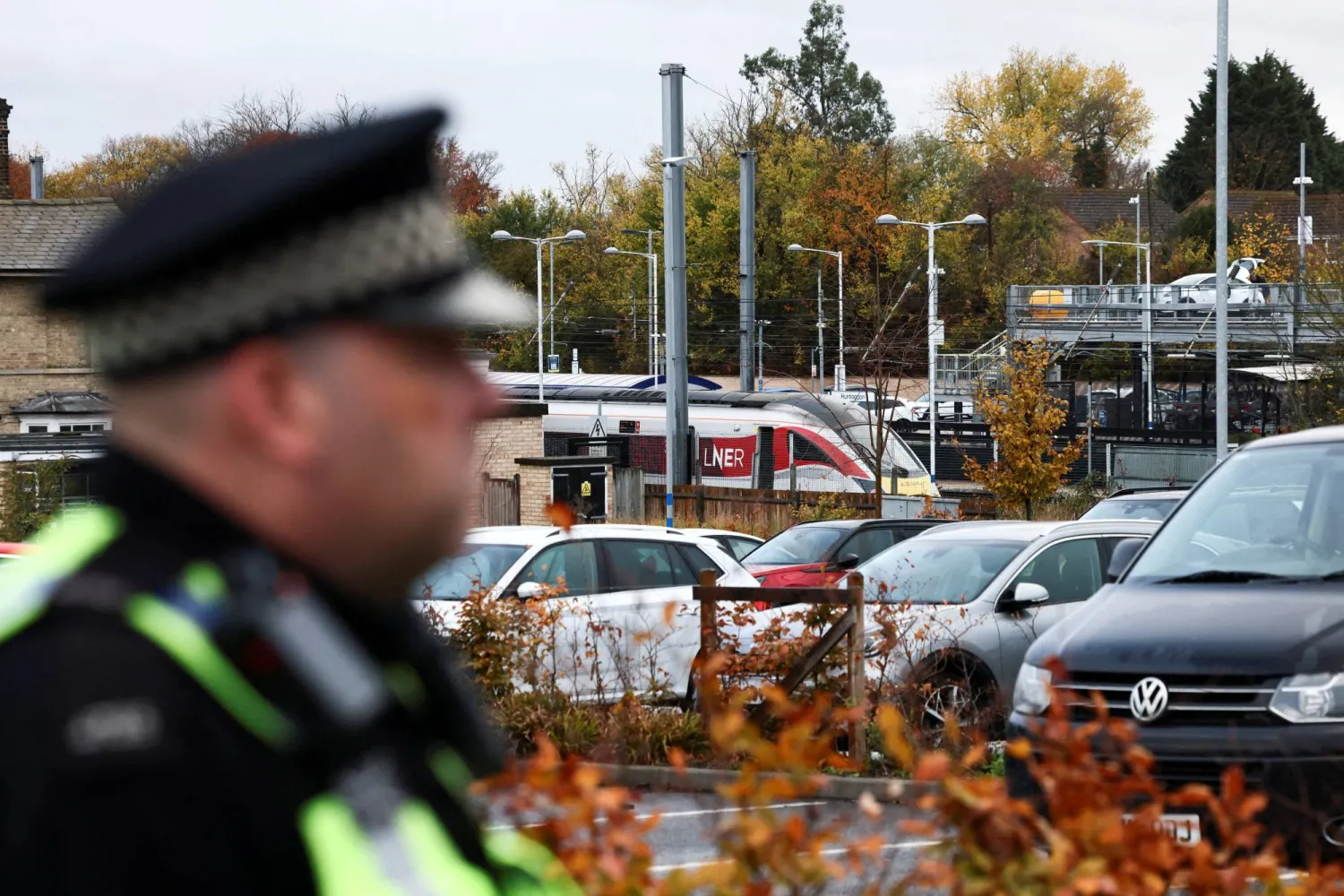 ضابط شرطة يراقب قطار «شركة لندن الشمالية الشرقية للسكك الحديدية» الذي وقعت على متنه سلسلة من عمليات الطعن... وهو متوقف على رصيف بمحطة هانتينغتون بالقرب من كامبريدج يوم 2 نوفمبر 2025 (رويترز)